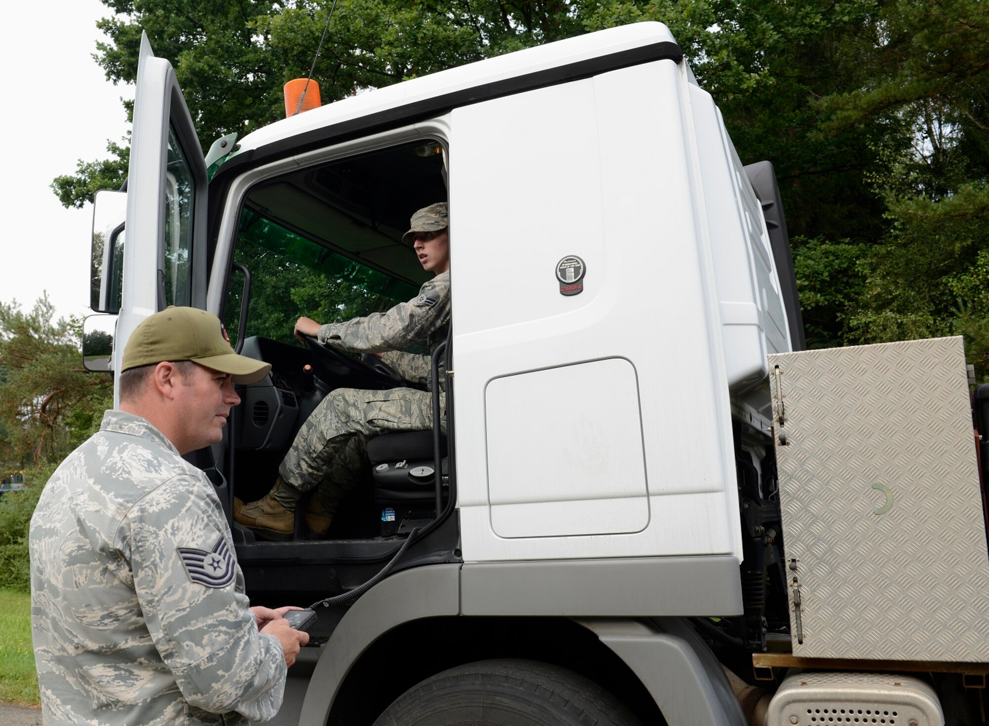 Airman 1st Class Richard Zeren, 786th Civil Engineer Squadron heavy equipment operator, waits for the green light from Tech. Sgt. John Lillis, 435th Construction and Training Squadron pavement and operator NCO in charge, to back up a tractor trailer vehicle so it hitches to a flatbed during the Air Force Civil Engineer Center Tractor Trailer Training program Aug. 10, 2015, at Ramstein Air Base, Germany. This is the first time this program is being taught in U.S. Air Forces in Europe, and the program teaches students how to safely drive and maneuver tractor trailers and includes an average of 58 hours of behind-the-wheel training. (U.S. Air Force photo/Airman 1st Class Tryphena Mayhugh) 