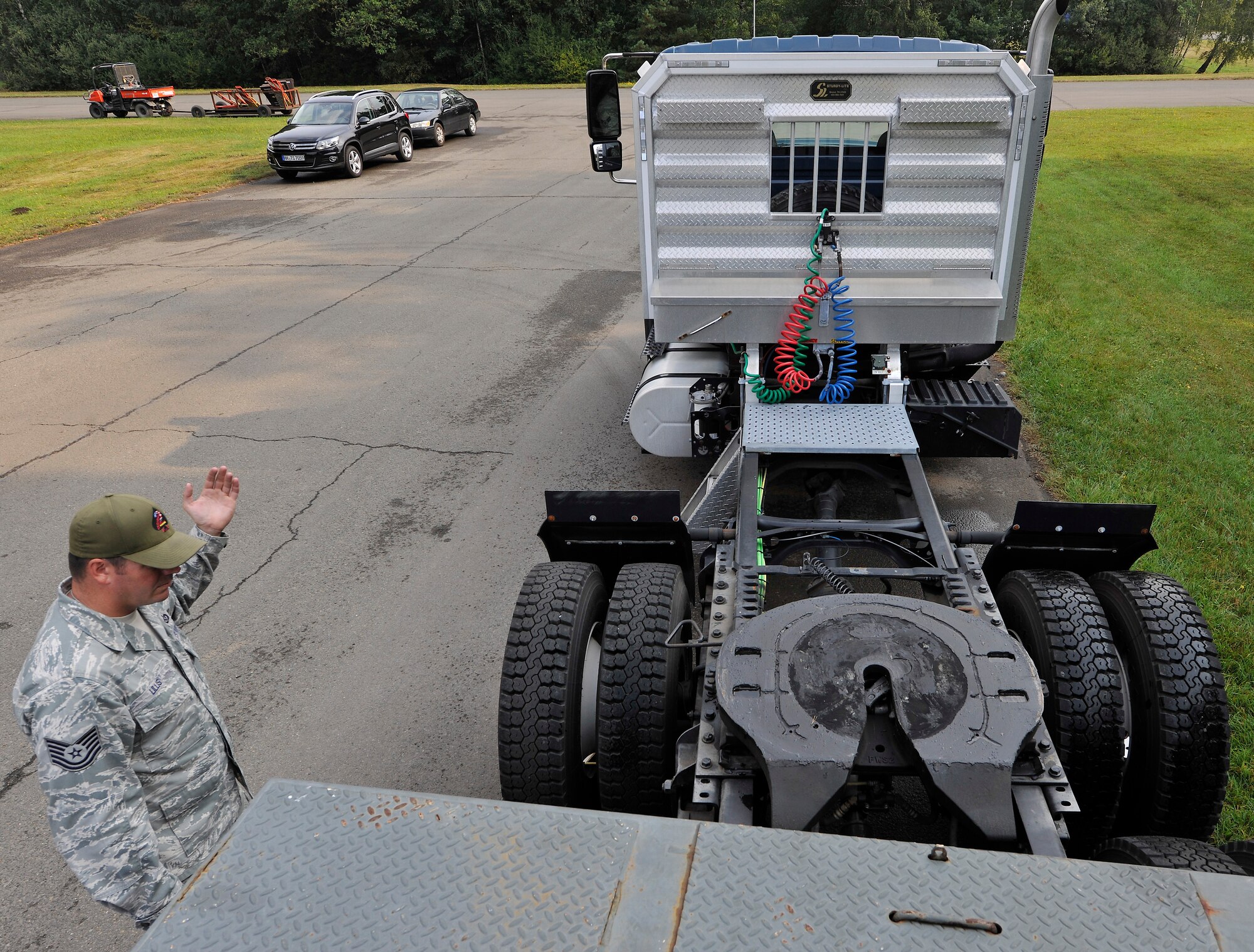Tech. Sgt. John Lillis, 435th Construction and Training Squadron pavements and equipment NCO in charge, directs a student to back up a tractor trailer vehicle so it can be hitched to a flatbed during the Air Force Civil Engineer Center Tractor Trailer Training program Aug. 10, 2015, at Ramstein Air Base, Germany. This is the first time this program is being taught in U.S. Air Forces in Europe. In it, students learn tractor trailer general knowledge, vehicle inspections, shifting proficiency, advanced backing maneuvers and over-the-road operating skills. (U.S. Air Force photo/Airman 1st Class Tryphena Mayhugh)