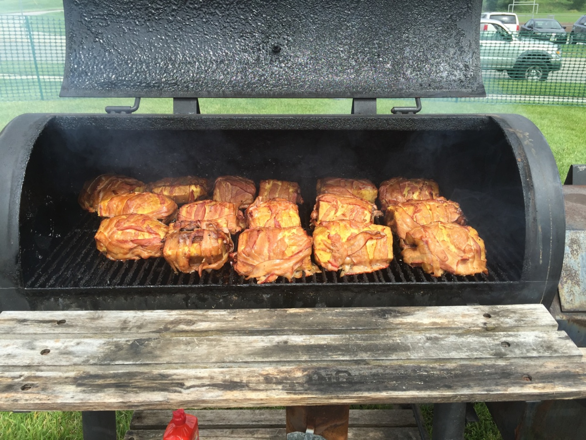 Swine Apples, smoked pork ribs stuffed in a pineapple that is then wrapped in bacon and smoked again, sit on the grill ready for 3rd Annual Bacon Fest attendess to enjoy Aug. 8 at the Ray & Joan Kroc Corps Community Center. Five Airmen from the 55th Force Support Squadron made up the “Dad Bods n Tasty Hogs” team who took first place in the Best Savory Category with the Swine Apples. (Courtesy photo)