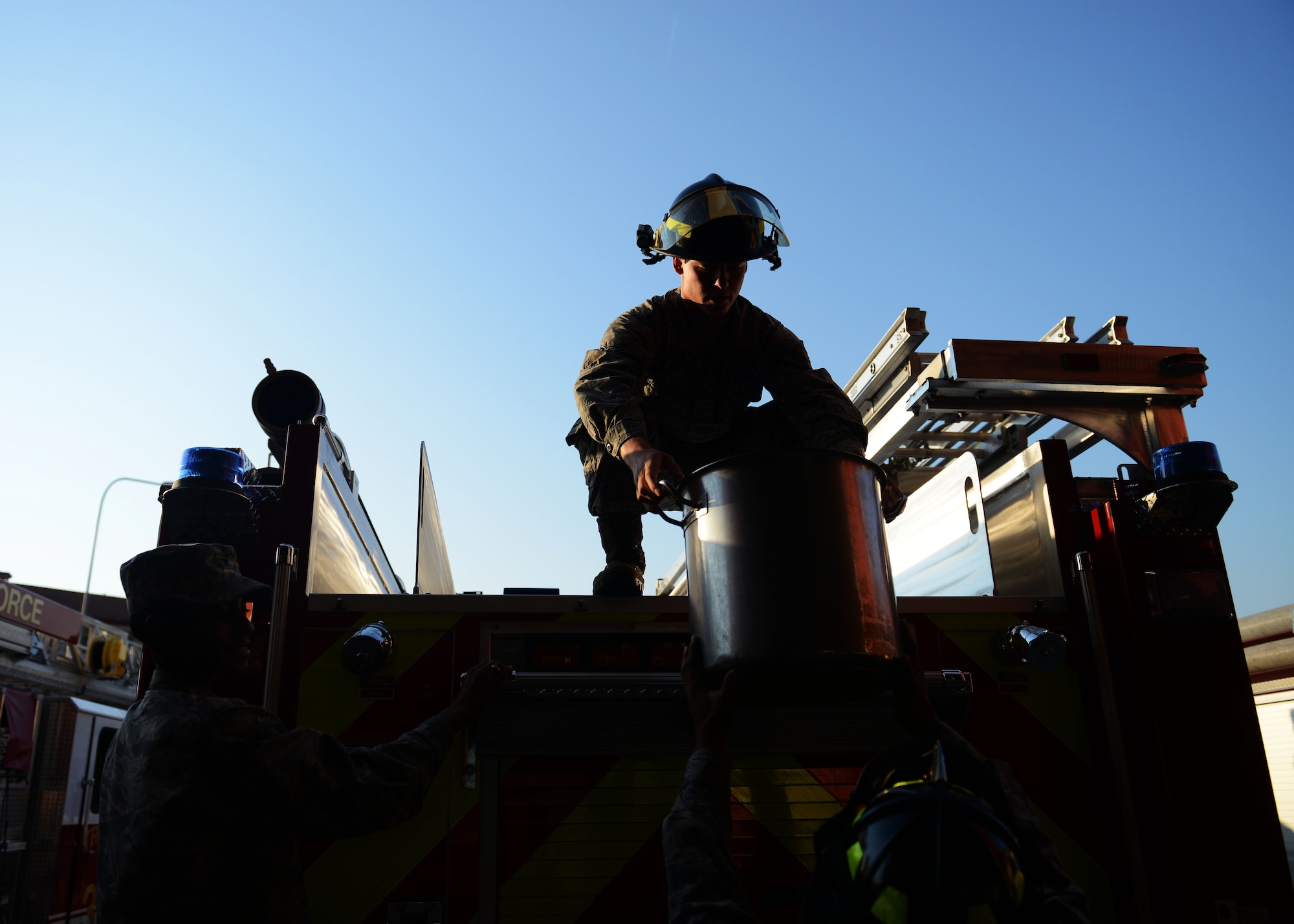 U.S. Air Force Airman 1st Class Grey Tedford, 31st Civil Engineer Squadron firefighter, lifts a bucket of water onto Engine 11 during the traditional  “Housing Ceremony for New Fire Apparatus,” Aug. 13, 2015, at Aviano Air Base, Italy. The transferring of water declares the new engine ready for use and a part of the unit. (U.S. Air Force photo by Airman 1st Class Deana Heitzman/Released)  