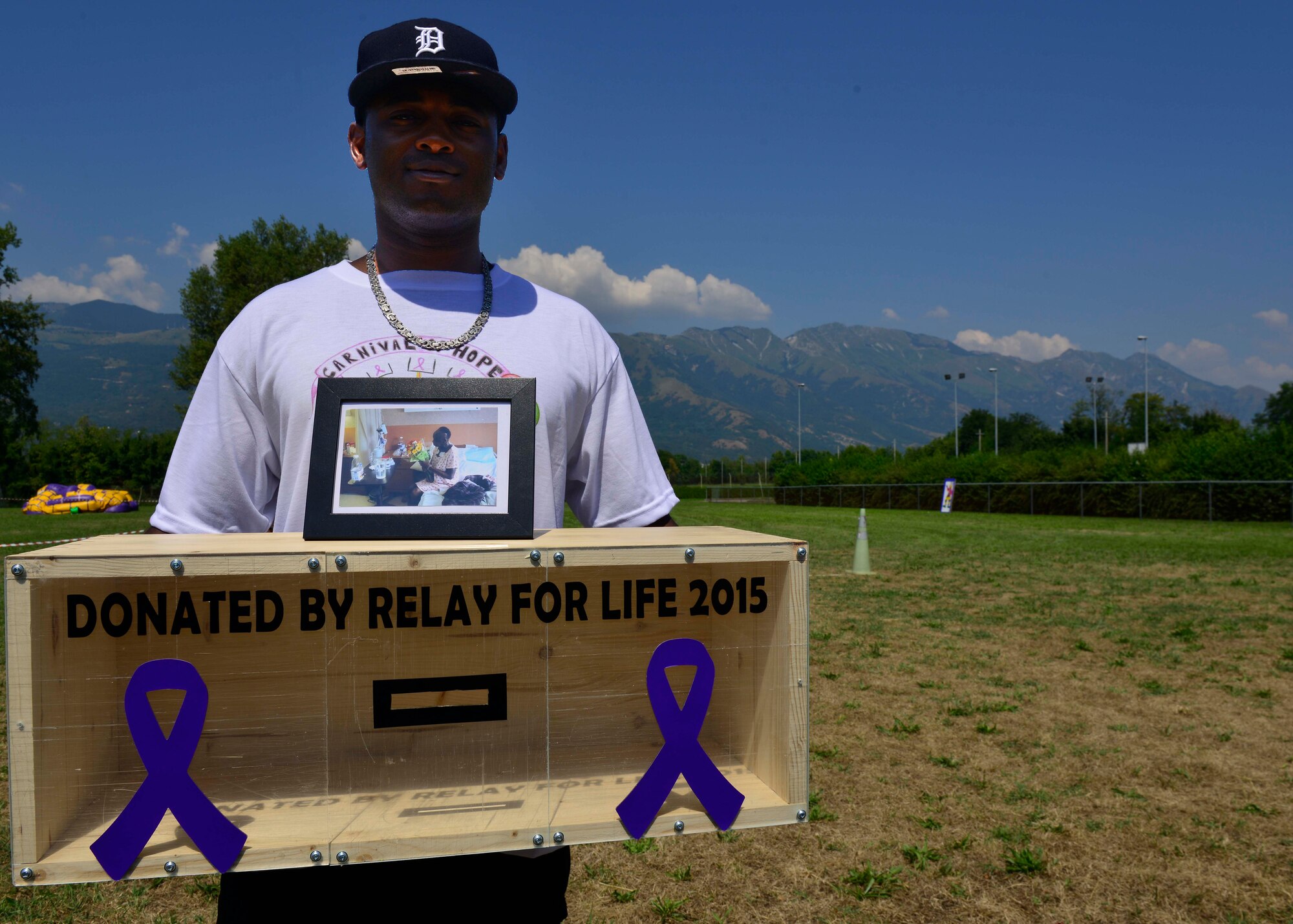 U.S. Air Force Staff Sgt. Darius Charles, 31st Communications Squadron client systems technician, holds a donation box during a Relay for Life event, Aug. 7, 2015, at Aviano Air Base, Italy. Charles built the box in honor of his aunt who recently passed away from cancer. (U.S. Air Force photo by Airman 1st Class Cary Smith/Released)