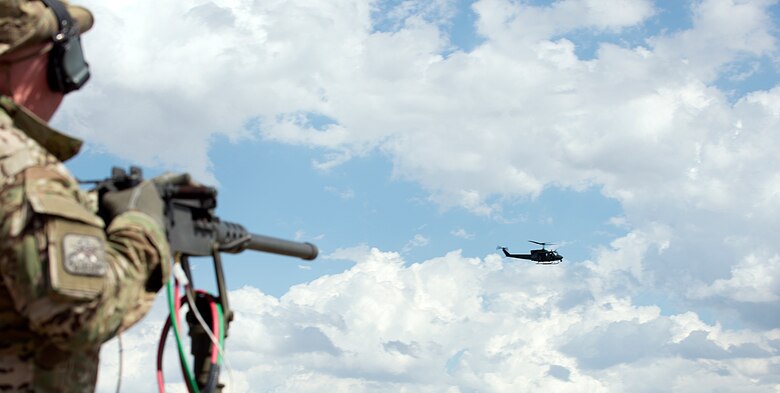 An evaluator directs simulated gun fire towards a UH-1N Huey helicopter belong to the 54th Helicopter Squadron, Minot Air Force Base, N.D., as its crew surveys an enemy-occupied, deactivated, Peacekeeper launch facility near Wheatland, Wyo., Aug. 10, 2015, during the helicopter operations portion of the 2015 Global Strike Challenge. Three hostile targets had to be located and eliminated before the helicopter crews were allowed to land and recapture the facility. (U.S. Air Force photo by Airman 1st Class Brandon Valle/Released)
