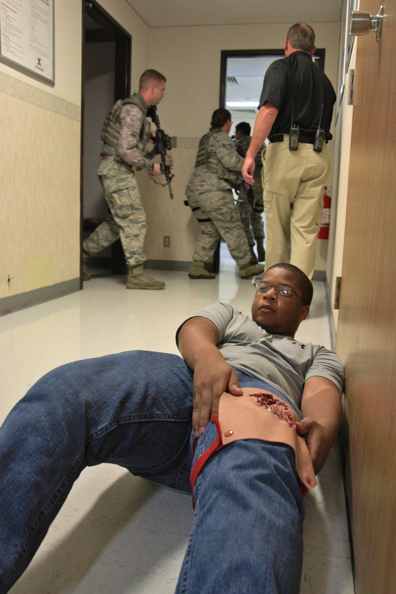 A role player lays on the floor as security forces personnel pursue a gunman as part of an active-shooter threat exercise at Misawa Air Base, Japan, Aug. 14, 2015. Simulating realistic scenarios of what security response force members might encounter provides them with valuable experience when reacting to unpredictable environments. (U.S. Air Force photo by Senior Airman Jose L. Hernandez-Domitilo/Released)