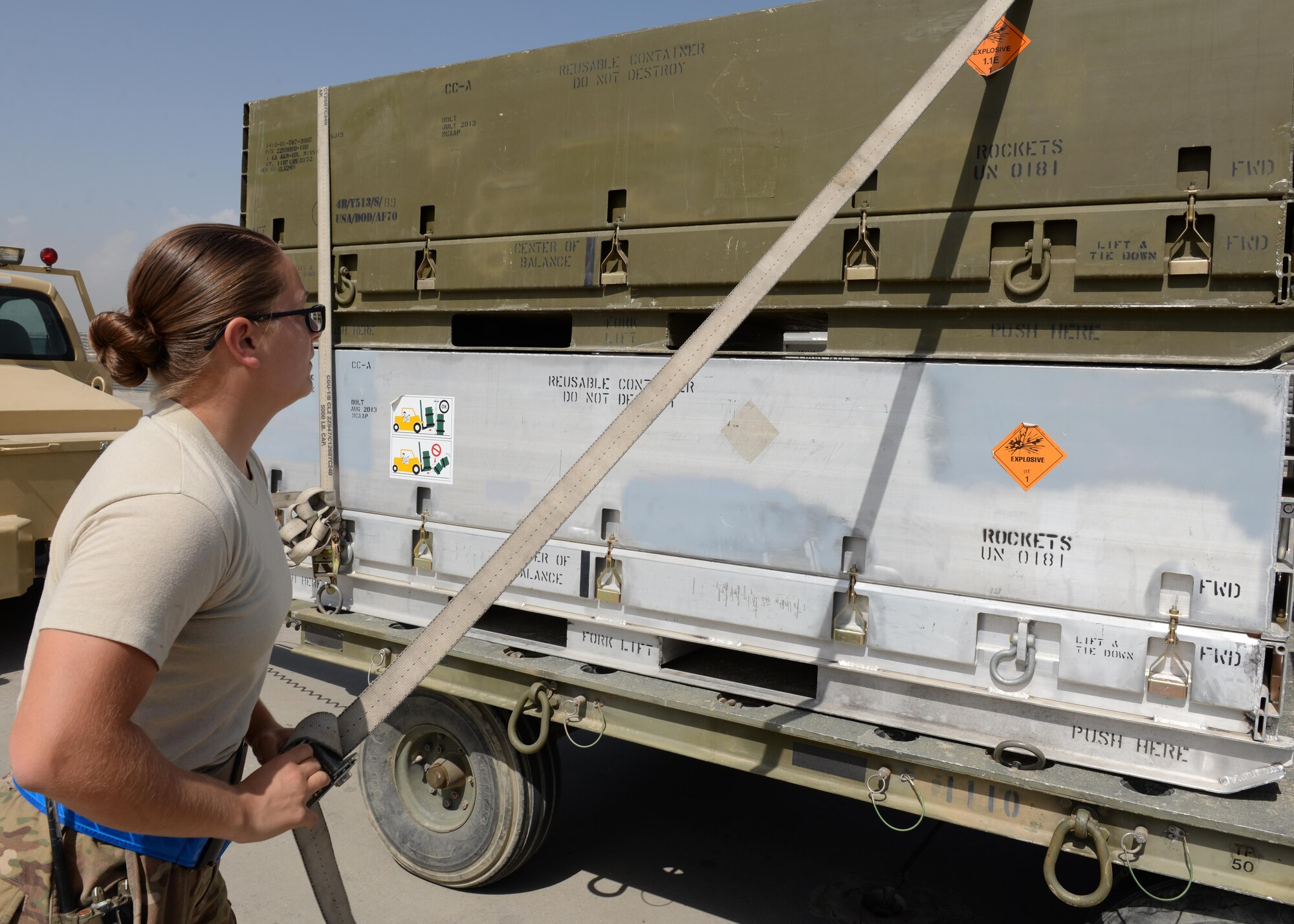 U.S. Air Force Airman First Class Morgan Strausser, 455th Expeditionary Maintenance Squadron line delivery crew chief, takes the locking straps off on munitions containers before loading them onto an F-16 Fighting Falcon aircraft Aug. 12, 2015, at Bagram Airfield, Afghanistan. Strausser is responsible for loading and unloading ammo from the F-16 Fighting Falcon aircraft here. (U.S. Air Force photo by Senior Airman Cierra Presentado/Released)