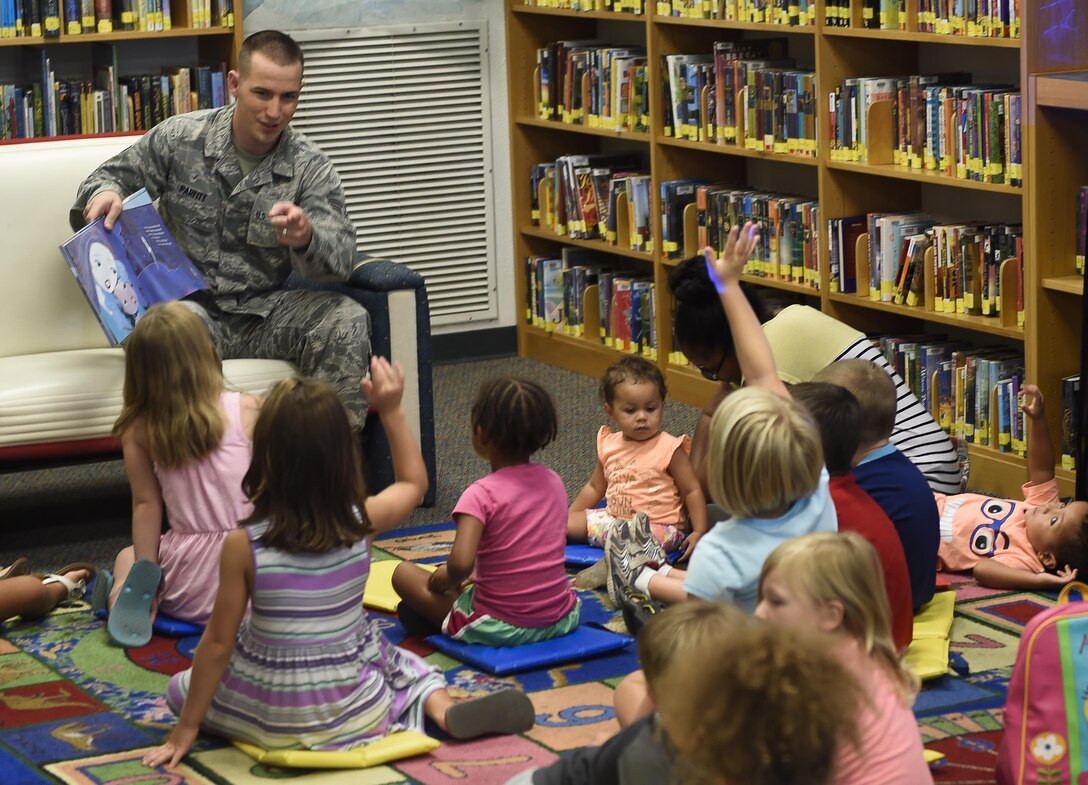 Senior Airman Joshua Parfitt, 23rd Special Operations Weather Squadron weather technician, reads to children at the library on Hurlburt Field, Fla., Aug. 6, 2015. This week’s story time was led by Airmen from the 23rd SOWS as part of a scheduled, tri-annual visit to help teach children about weather systems. (U.S. Air Force photo by Airman Kai White/Released)