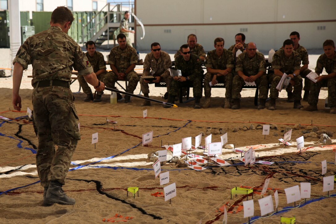 A British soldier with 2nd Marine Expeditionary Brigade explains the terrain model to a crowd of U.S. Marines, Canadian and British at a rehearsal of concept drill at Camp Wilson aboard Marine Corps Air Ground Combat Center, Calif., in support of the 2nd MEB Large Scale Exercise Aug. 12, 2015. LSE is a combined U.S. Marine Corps, Canadian, and British exercise conducted at the Brigade-level, designed to enable live, virtual and constructive training for participating forces.