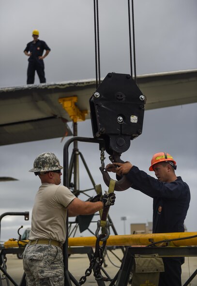 Tech. Sgt. Frank Cavaliere, 1st Special Operations Civil Engineer Squadron pavement and equipment operator craftsman, and Staff Sgt. Michael Hill, 402nd Expeditionary Depot Maintenance team depot level maintenance journeyman, Robins Air Force Base, Ga., prepare to remove the wing of an MC-130P Combat Shadow on Hurlburt Field, Fla., Aug. 5, 2015. Wing removal enabled the MC-130P to be towed safely from the flightline to the Hurlburt Field Air Park Aug. 15, 2015. (U.S. Air Force photo by Airman Kai White/Released)
