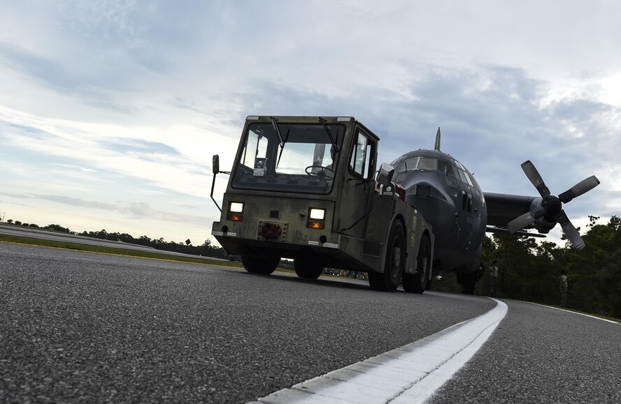 An MC-130P Combat Shadow is towed down Independence Road, Aug. 15, 2015, on Hurlburt Field, Fla. The Combat Shadow was towed from the flightline and staged for installation in the Hurlburt Field Air Park. The MC-130P fleet was retired May 15, 2015, after more than 25 years of service. The installation process for this aircraft known as “Team Shadow,” is scheduled for completion by Sept. 6, 2015. (U.S. Air Force photo by Airman 1st Class Ryan Conroy/Released) 
