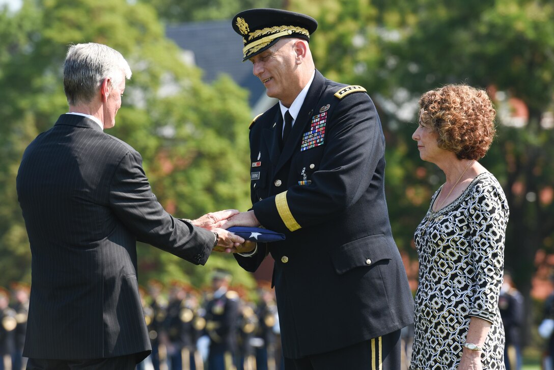 Army Secretary John M. McHugh presents outgoing Army Chief of Staff Gen. Ray Odierno with an American flag to mark his retirement as his wife, Linda, looks on during in a ceremony on Joint Base Myer-Henderson Hall, Va., Aug. 14, 2015. During the event, Odierno relinquished duties to Army Gen. Mark A. Milley.
