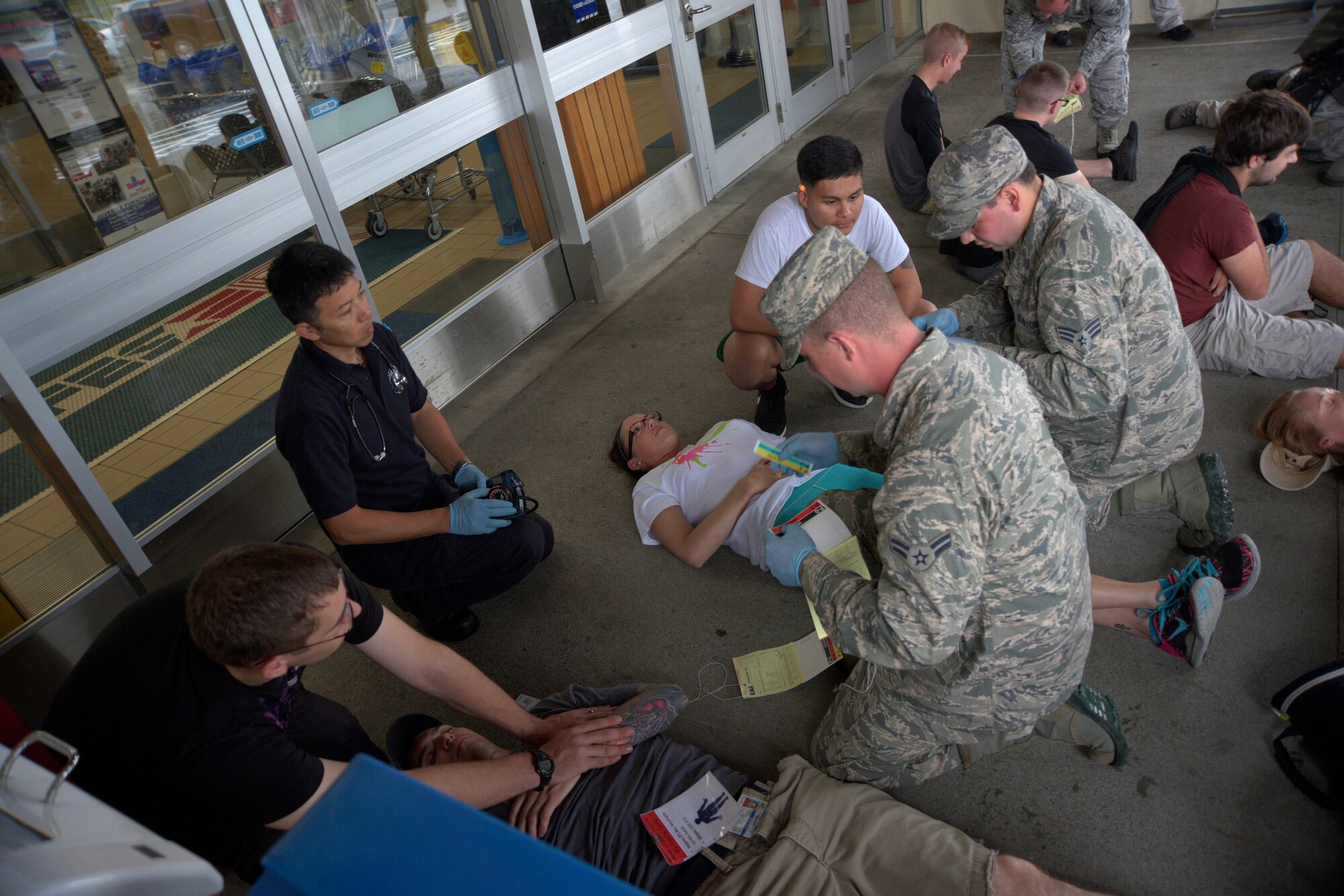 Fire Protection Specialists from the 35th Civil Engineer Squadron identify wounds on mock injured victims during an active-shooter threat exercise at Misawa Air Base, Japan, Aug. 15, 2015. Emergency responders from the fire department and 35th Medical Group enter the scene to provide assistance to wounded or injured victims following the neutralization of an active-shooter threat. (U.S. Air Force photo by Senior Airman Jose L. Hernandez-Domitilo/Released)