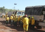 A CH-47 Chinook belonging to the California Army National Guard flies overhead as members of Crew 9, Task Force Charlie, listen to a safety briefing by CAL FIRE military liaison Sean Sunahara Aug. 14, 2015, near Clearlake, California. The Soldiers were at a staging area prior to heading into a contained area during the Jerusalem Fire. 
