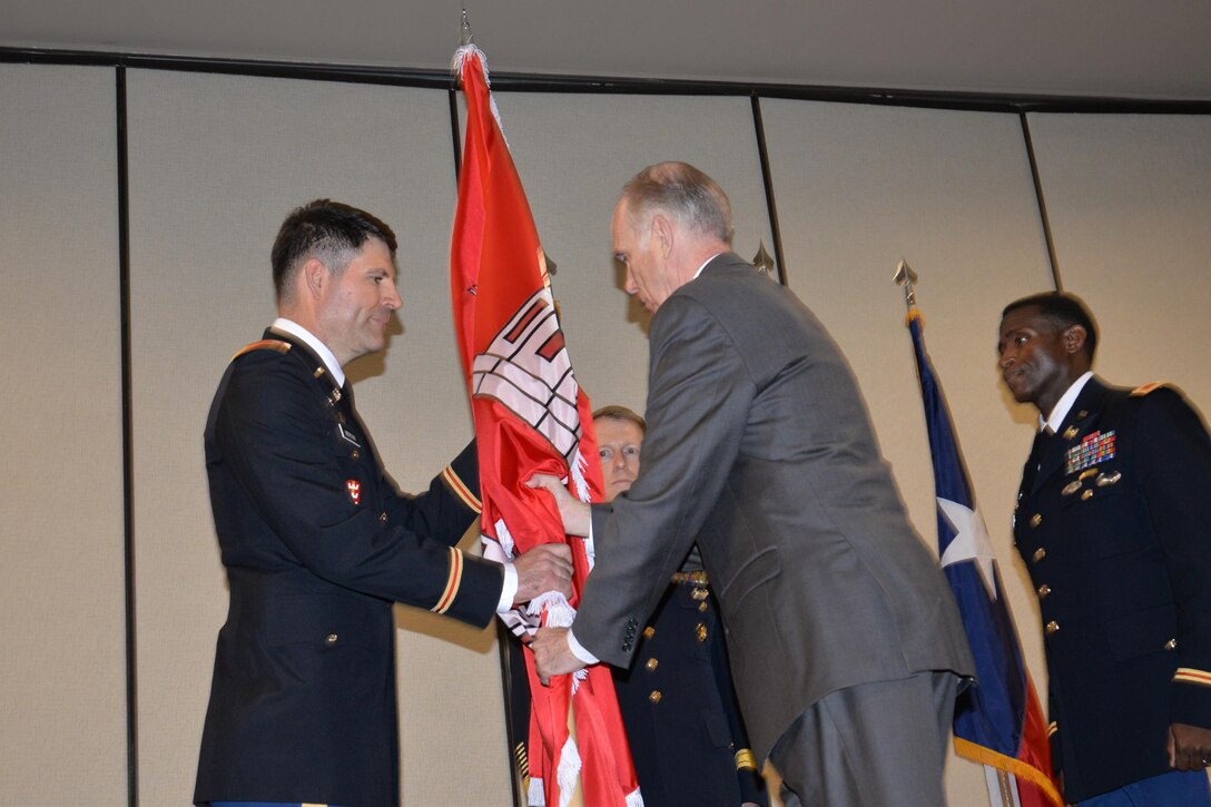 The out-going commander, Lt. Col. Clay Morgan receives the unit flag from the "keeper of the colors" while the in-coming commander, Col. Calvin Hudson, II looks on during the Aug. 14 Assumption of Command Ceremony in Fort Worth, Texas.