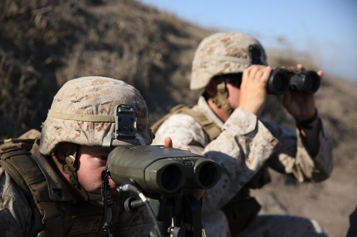 Corporal Brady Davenport (left), a fire support man, and 1st Lt. Mark Null (right), an artillery officer, both assigned to 2nd Battalion, 11th Marine Regiment, 1st Marine Divison, observe impacts from M777 Howitizers aboard Marine Corps Base Camp Pendleton, Calif., Aug. 14, 2015. 2/11 annually conducts Summer Fire Exercise to sustain core proficiencies and to further develop their ability to execute fire missions.