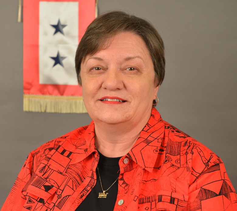 Martha Coley, mother to two retired Air Force pilots and an accountant in the Resource Management Division, is a face of the nationwide Blue Star Mothers of America organization that lists more than 6,000 mothers of armed forces service members across approximately 200 locations. Behind her is BSMA’s service flag, an official, indoor banner displayed by members of its organization. According to the organization’s website, the flag should be flown facing out from the front window of a home or organization. Each blue star on the flag represents a past or present service member.