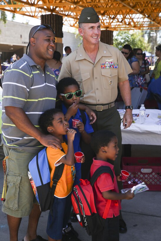 Col. John Farnam, commanding officer of Marine Corps Air Station Miramar, California, poses with a family during the Military Family Enrollment and Appreciation Fair hosted by the San Diego Unified School District at Serra High School, Aug. 15. The fair offered military families an opportunity to enroll their children in school while enjoying games, prizes and a complimentary lunch.