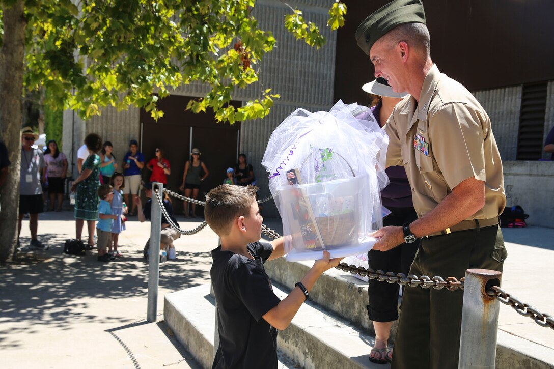 Col. John Farnam, commanding officer of Marine Corps Air Station Miramar, California, hands a prize to a student during the Military Family Enrollment and Appreciation Fair hosted by the San Diego Unified School District at Serra High School, Aug. 15. The fair offered military families an opportunity to enroll their children in school while enjoying games, prizes and a complimentary lunch.