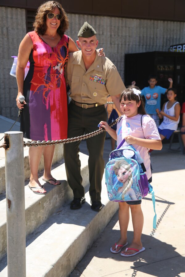 Col. John Farnam, commanding officer of Marine Corps Air Station Miramar, California, poses with families during the Military Family Enrollment and Appreciation Fair hosted by the San Diego Unified School District at Serra High School, Aug. 15. The fair offered military families an opportunity to enroll their children in school while enjoying games, prizes and a complimentary lunch.