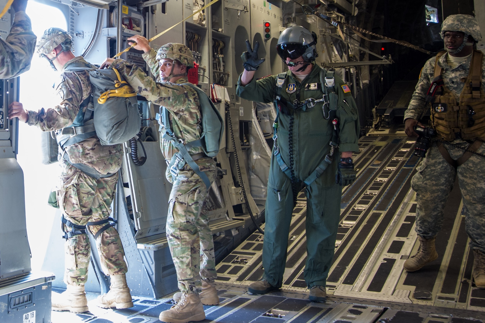 Master Sgt. Al Larson, 701st Airlift Squadron loadmaster and former U.S. Army paratrooper, communicates with hand signals during a flight over Lawson Army Airfield, Fort Benning, Ga. Aug. 15, 2015. Reserve aircrews from the 701st and 300th AS out of Joint Base Charleston, S.C. flew two C-17s during Fort Benning’s celebration of the 75th anniversary of the U.S. Army Airborne School. Almost 300 paratroopers took the big leap in the day’s event. (U.S. Air Force photo by Staff Sgt. Bobby Pilch)