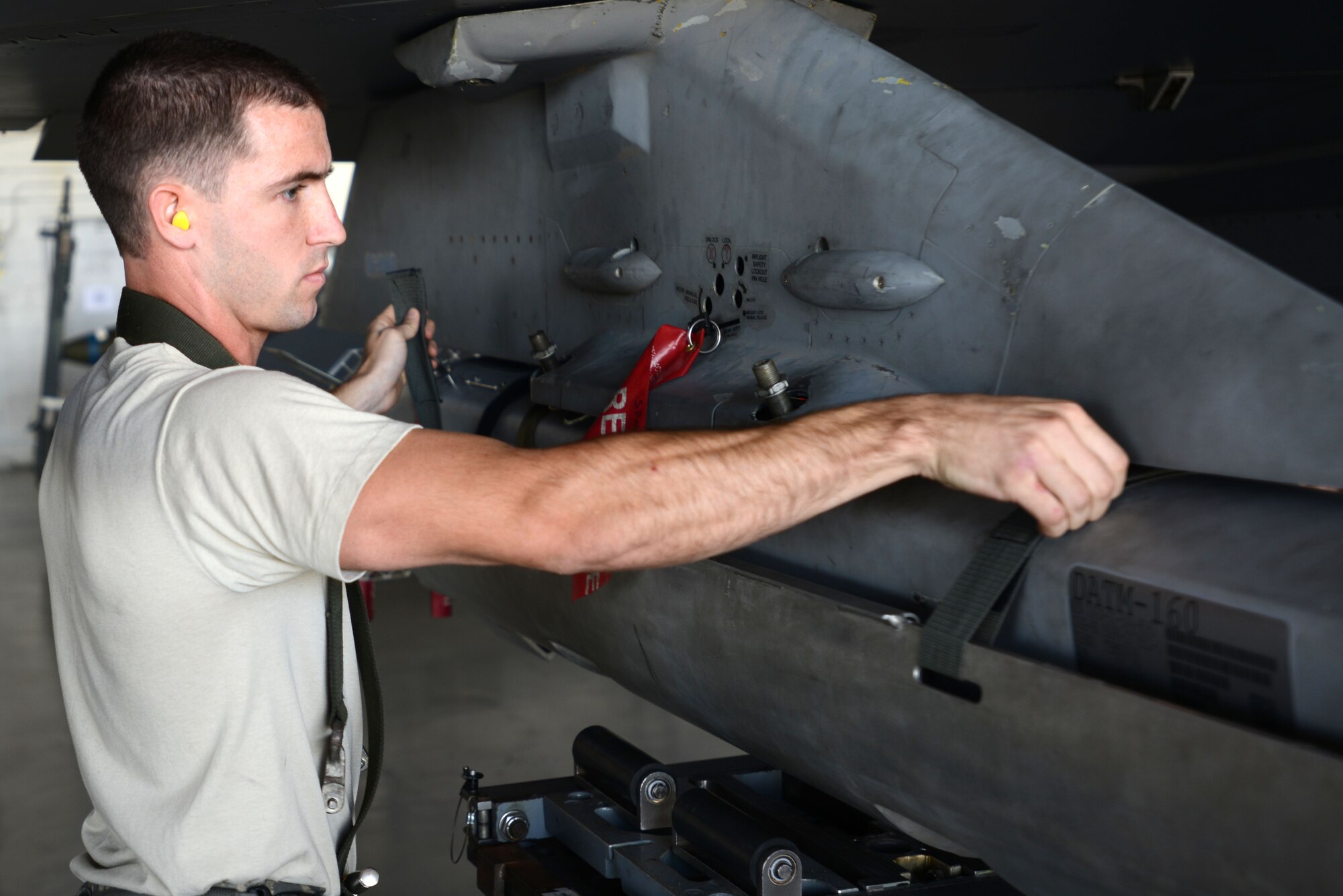 U.S. Air Force Airman 1st Class Madden McCall, 20th Aircraft Maintenance Squadron, 55th Aircraft Maintenance Unit weapons load crew member, secures a munition to the wing of an F-16CM Fighting Falcon during a weapons load crew of the quarter competition at Shaw Air Force Base, S.C., Aug. 14, 2015. Three-man teams from the 55th, 77th, and 79th AMUs, along with the 20th Equipment Maintenance Squadron, competed to determine who the best weapons load crew on base was. (U.S. Air Force photo by Airman 1st Class Kelsey Tucker/Released)