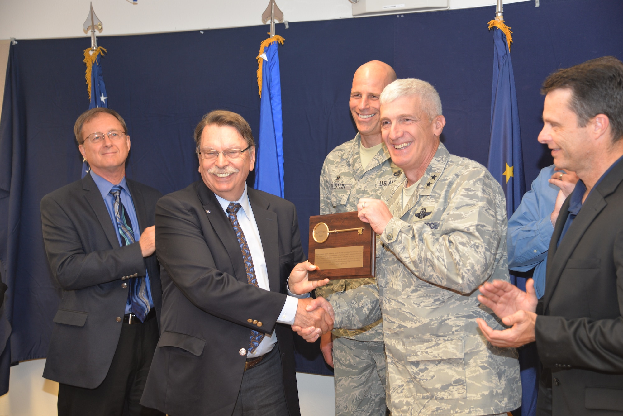 Brian Rogers, University of Alaska-Fairbanks chancellor, accepts the ceremonial key to the High Frequency Active Auroral Research Program, better known as HAARP, in Gakona, Alaska, from Maj. Gen. Thomas Masiello, Air Force Research Laboratory commander, August 11. The ionospheric research facility was transferred from the Air Force to the university to allow for continued exploration via a land-use cooperative research and development agreement. (Photo by Tommie Baker)