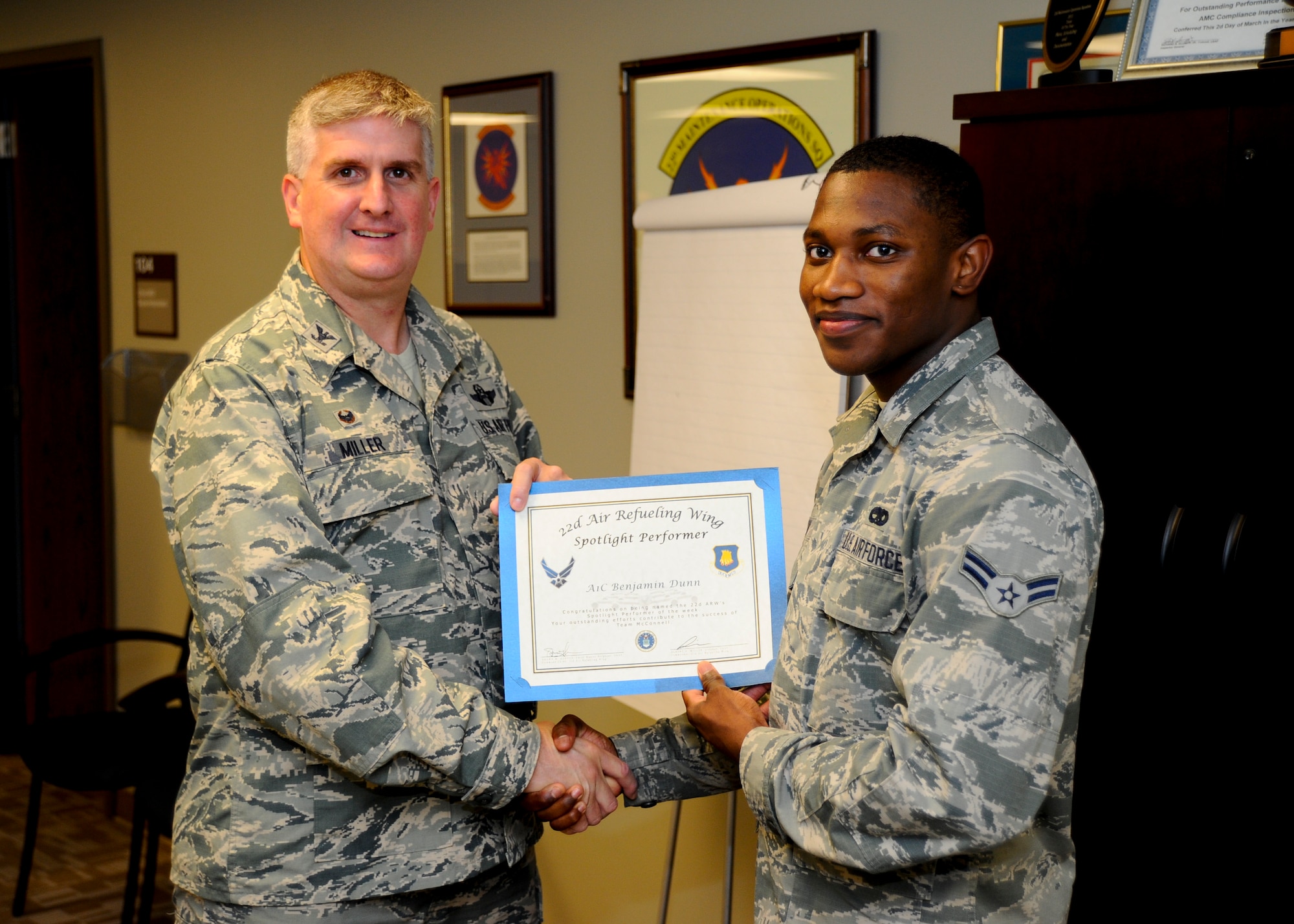 Airman 1st Class Benjamin Dunn, 22nd Maintenance Group maintenance scheduling journeyman, poses with Col. Albert Miller, 22nd Air Refueling Wing commander, Aug. 13, 2015, at McConnell Air Force Base, Kan. Dunn was recognized as the spotlight performer for the week of Aug. 9 – 15, for his consistent and hard work. (U.S. Air Force photo by Senior Airman Victor J. Caputo)
