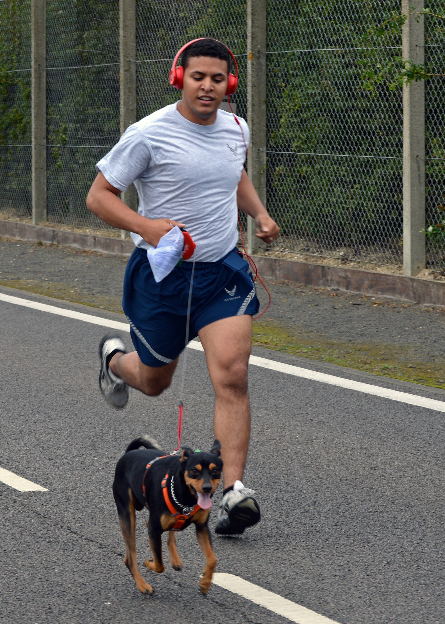 U.S. Air Force Airman 1st Class Glenn Gonzalez-Diaz, 100th Force Support Squadron customer support journeyman from Ellington, Conn., runs with his dog Tommy  at the monthly 5k run Aug. 14, 2015, on RAF Mildenhall, England. The run encourages morale and camaraderie throughout the base through exercise and healthy competition. (U.S. Air Force photo by Senior Airman Christine Halan/Released)