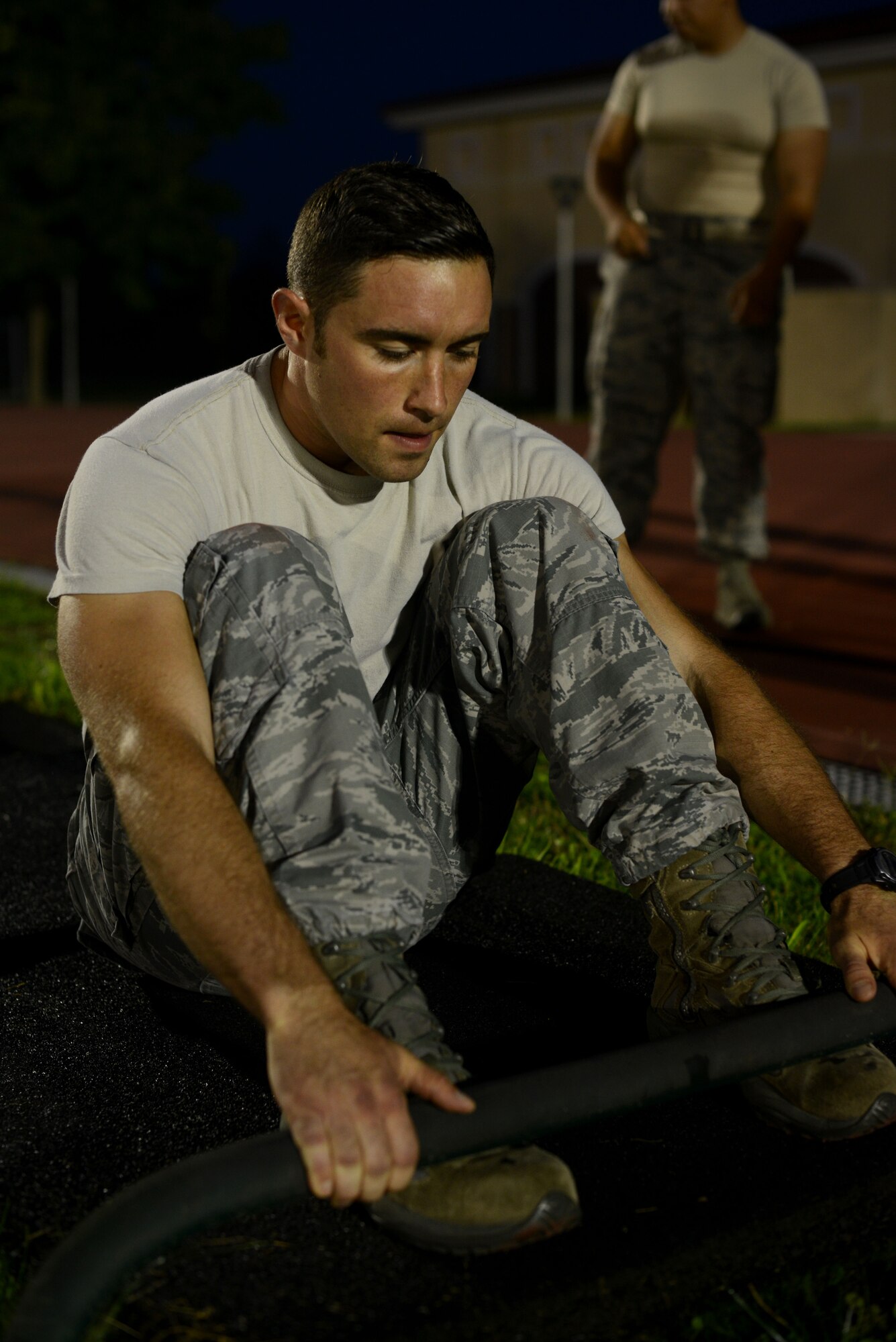 U.S. Air Force Staff Sgt. R.J. Biermann, 31st Fighter Wing public affairs photojournalist, places his feet in a toe-hold bar before the situp portion of an Army pre-Ranger physical assessment, Aug. 5, 2015 at Aviano Air Base, Italy. Biermann and several Aviano Airmen participated in the pre-Ranger course which included a 5-mile run, pushups, situps and chinups. (U.S. Air Force photo by Staff Sgt. Evelyn Chavez/Released)