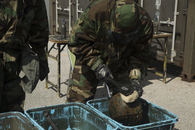 A Marine scrubs his helmet during a decontamination drill at Camp Hansen, Okinawa, July 30, 2015. Marines and Japan Ground Self-Defense Force soldiers participated in a combined integrated capabilities demonstration to identify how both units can benefit each other. The Marines are with Chemical, Biological, Radiological, and Nuclear Platoon, Headquarters Battalion, 3rd Marine Division, III Marine Expeditionary Force, and Battery A, 1st Battalion, 12th Marine Regiment, under the Unit Deployment Program. 