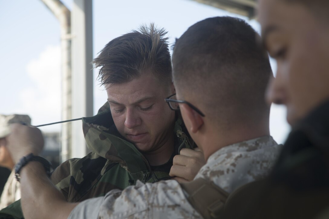 Marines don Mission Oriented Protective Posture suits before a simulated chemical, biological, radiological and nuclear reconnaissance and decontamination demonstration with the Japan Ground Self-Defense Force at Camp Hansen, Okinawa, July 30, 2015. The troops participated in a combined integrated capabilities demonstration to identify how both units can benefit each other. The Marines are with CBRN Platoon, Headquarters Battalion, 3rd Marine Division, III Marine Expeditionary Force and Battery A, 1st Battalion, 12th Marine Regiment, under the Unit Deployment Program. The JGSDF soldiers are with Nuclear, Biological, Chemical Unit, 15th Brigade. 