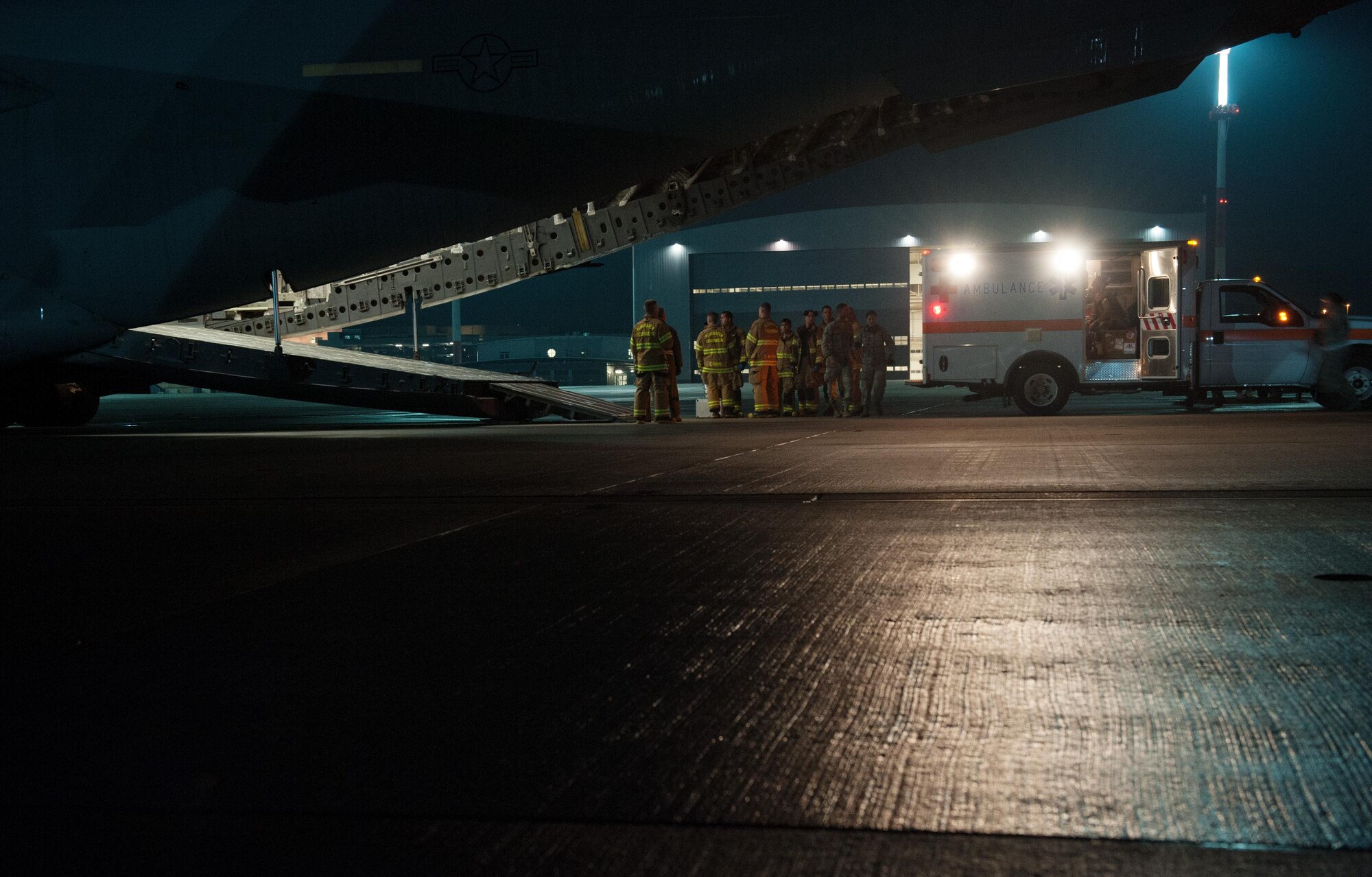 Firefighters and medical personnel standby to assist in the transport of a patient during an aeromedical evacuation mission on Aug. 9, 2015, at Ramstein Air Base, Germany. The personnel assisting in the mission were from the 86th Civil Engineer Squadron, Kaiserslautern Military Community Fire Emergency Services and personnel from the 10th Aeromedical Evacuation Operations Team and 455th Expeditionary Aeromedical Evacuation Squadron from Bagram Airfield, Afghanistan. (U.S. Air Force photo/Staff Sgt. Leslie Keopka)