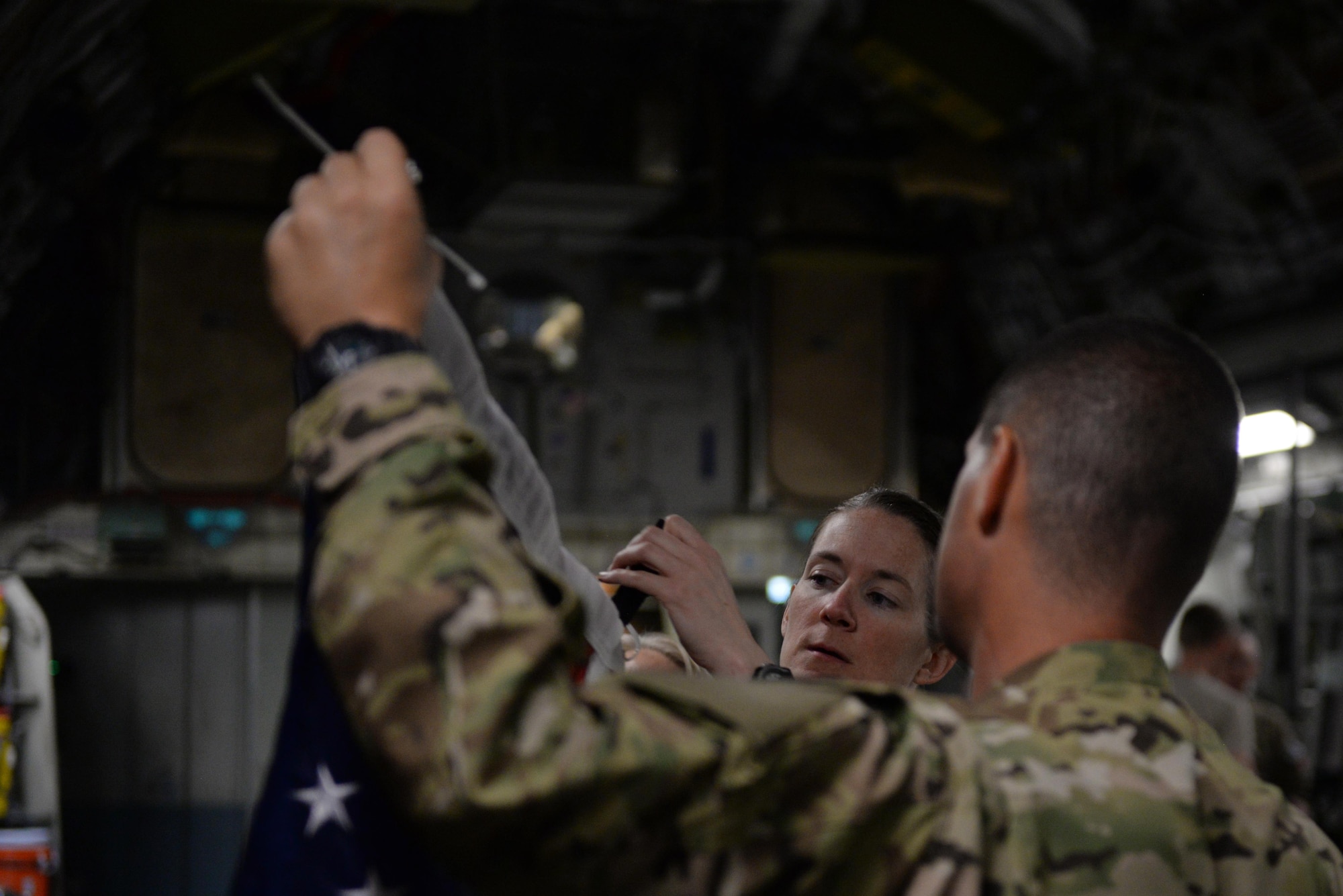 U.S. Air Force Senior Airman Margaret “Maggie” Mathewes, 455th Expeditionary Aeromedical Evacuation Squadron AE technician, and Tech. Sgt. Russell “Rusty” McLamb, left, 455th Expeditionary Aeromedical Evacuation Squadron AE technician deployed from the North Carolina Air National Guard’s 156th AES, hang a flag on a C-17 Globemaster III aircraft before an AE mission at Bagram Airfield, Afghanistan, Aug. 9, 2015.  The 455th EAES Airmen are charged with the responsibility of evacuating the sick and wounded from Central Command to higher echelons of medical care. (U.S. Air Force photo by Maj. Tony Wickman/Released)