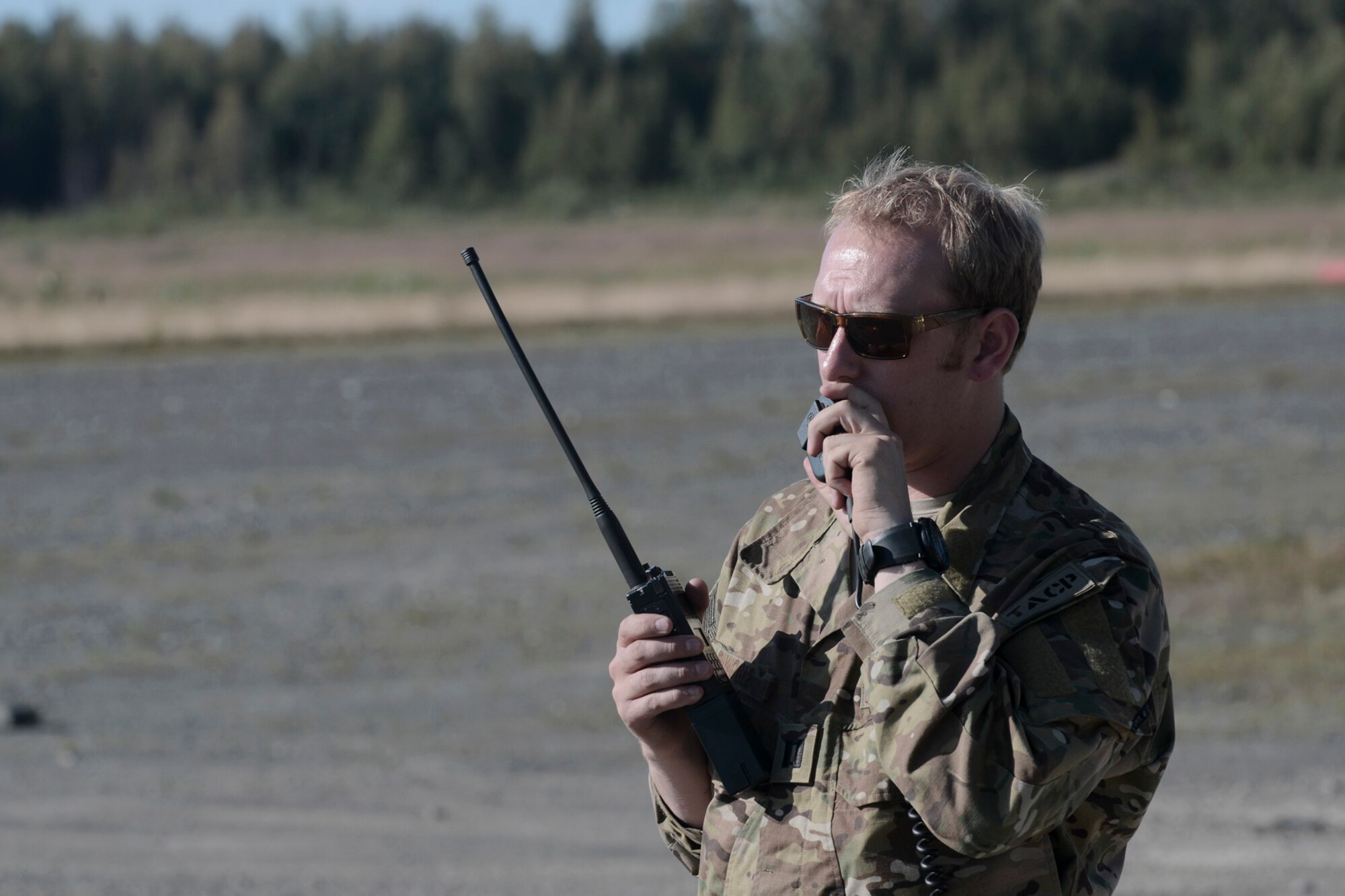 U.S. Air Force Capt. Michael Spanogle, 3rd Air Support Operations Squadron air mobility liaison officer, communicates with aircrew flying overhead a landing zone during RED FLAG-Alaska at Joint Base Elmendorf-Richardson, Alaska, Aug. 14, 2015. The training allowed C-130 aircrew to practice austere landings and take offs, combat offloads and supply drops, but also allowed friendly competition between participating Air Forces: U.S. Air Force, Japan Air Self-Defense Force, Royal Air Force, Royal Australian Air Force, Royal New Zealand Air Force and Royal Thai Air Force. Seasoned C-130 aircrew from each country judged the training exercises from the ground, allotting points based off predetermined timing and accuracy requirements. (U.S. Air Force photo by Staff Sgt. Cody H. Ramirez/Released)