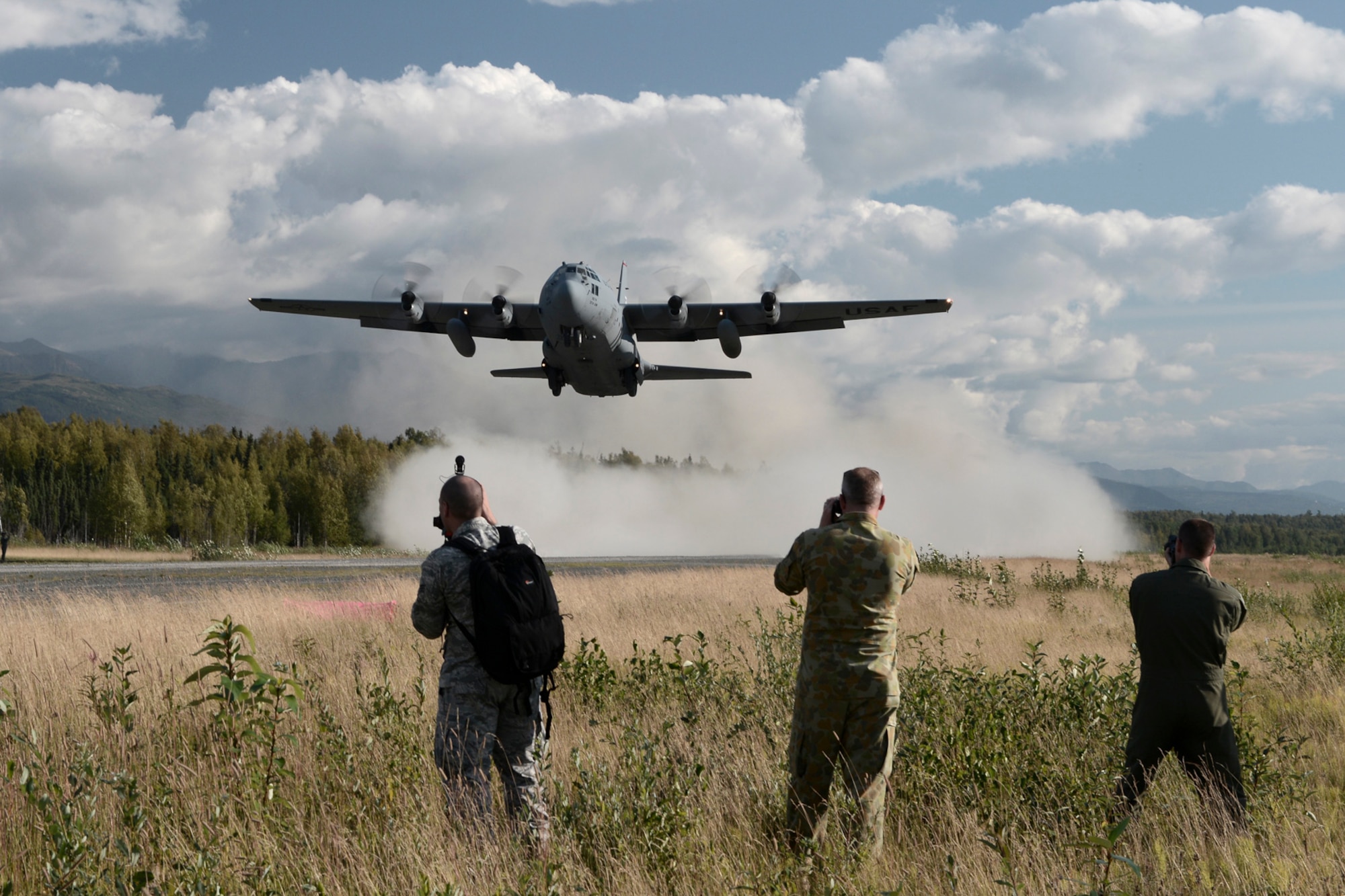 Observers watch a U.S. Air Force C-130 Hercules with the 36th Airlift Squadron from Yokota Air Base, Japan, take off of an austere runway used for training during RED FLAG-Alaska at Joint Base Elmendorf-Richardson, Alaska, Aug. 14, 2015. The training allowed C-130 aircrew to practice austere landings and take offs, combat offloads and supply drops, but also allowed friendly competition between participating Air Forces: U.S. Air Force, Japan Air Self-Defense Force, Royal Air Force, Royal Australian Air Force, Royal New Zealand Air Force and Royal Thai Air Force. Seasoned C-130 aircrew from each country judged the training exercises from the ground, allotting points based off predetermined timing and accuracy requirements. (U.S. Air Force photo by Staff Sgt. Cody H. Ramirez/Released)