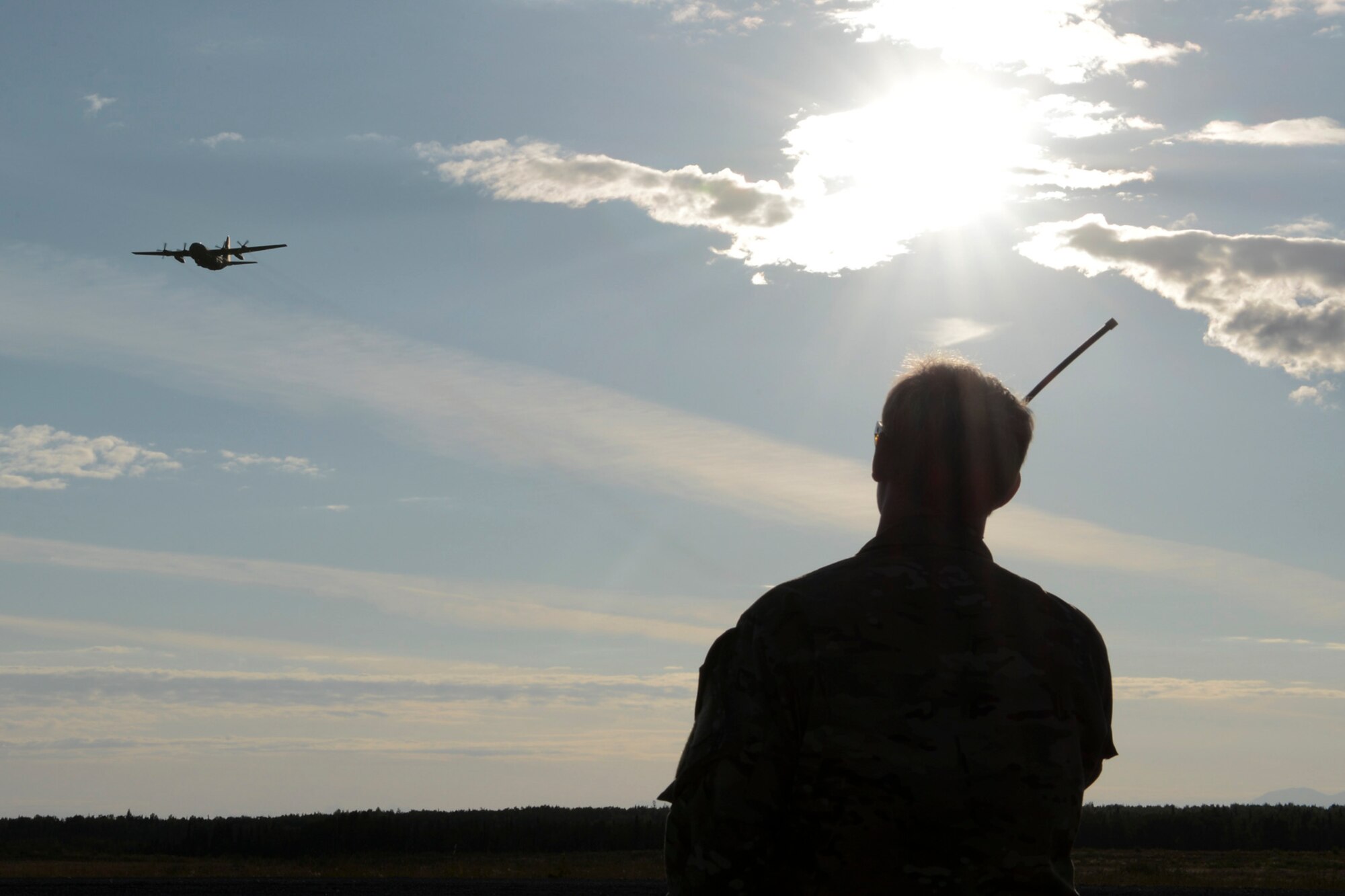 U.S. Air Force Capt. Michael Spanogle, 3rd Air Support Operations Squadron air mobility liaison officer, communicates with aircrew flying overhead a landing zone during RED FLAG-Alaska at Joint Base Elmendorf-Richardson, Alaska, Aug. 14, 2015. The training allowed C-130 aircrew to practice austere landings and take offs, combat offloads and supply drops, but also allowed friendly competition between participating Air Forces: U.S. Air Force, Japan Air Self-Defense Force, Royal Air Force, Royal Australian Air Force, Royal New Zealand Air Force and Royal Thai Air Force. Seasoned C-130 aircrew from each country judged the training exercises from the ground, allotting points based off predetermined timing and accuracy requirements. (U.S. Air Force photo by Staff Sgt. Cody H. Ramirez/Released)