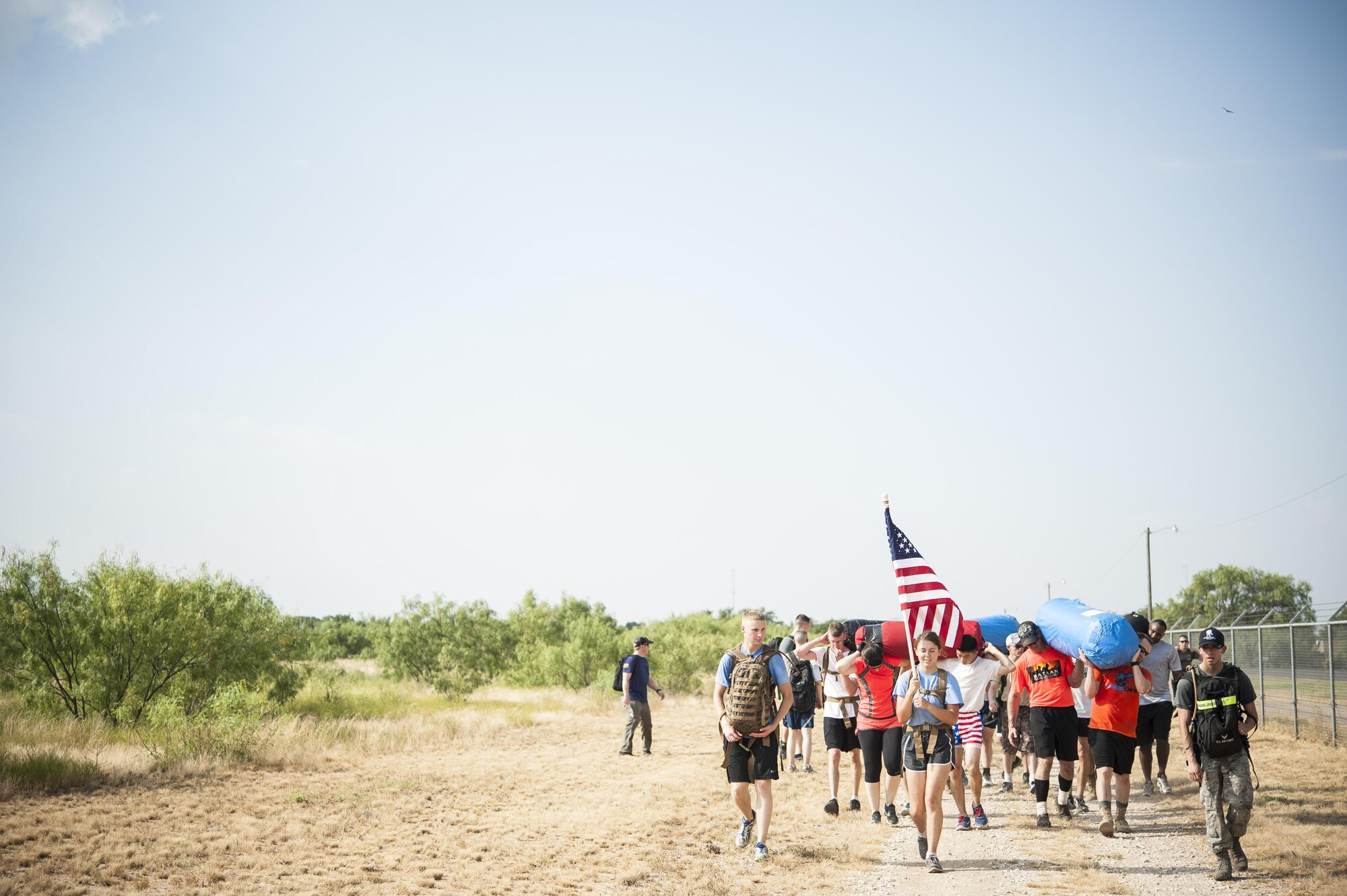 Participants of the Team Cohesion Challenge ruck march while carrying punching bags on perimeter road on Goodfellow Air Force Base, Texas, Aug. 15, 2015. The goal of the event was to encourage team building though strenuous physical activity and remove cultural biases between military services. (U.S. Air Force photo by Staff Sgt. Michael Smith/Released)