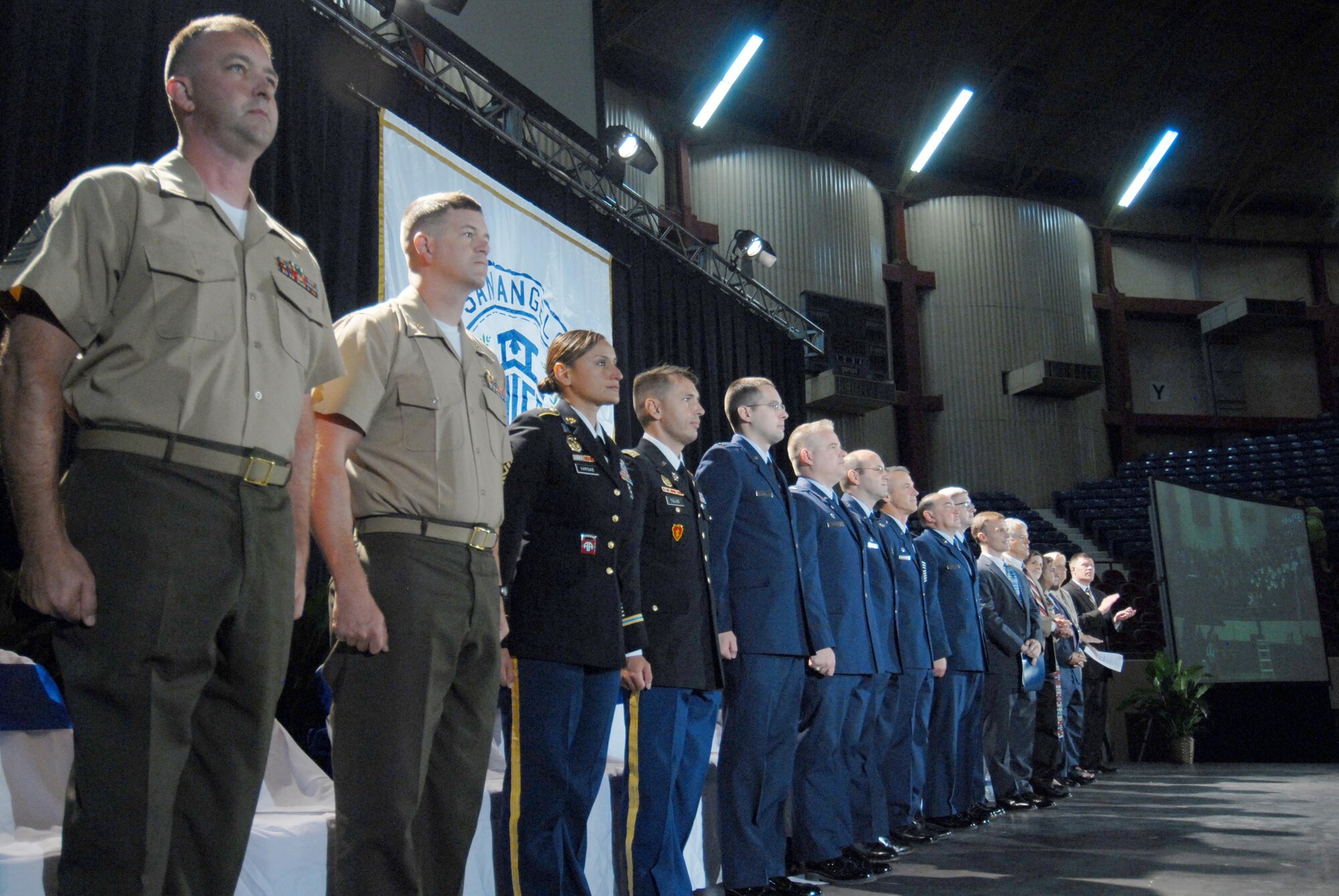 Goodfellow Air Force Base leadership stand at attention during the playing of “The Armed Forces Medley” at the San Angelo Independent School District convocation in the Foster Communication Coliseum, San Angelo, Texas, Aug. 18, 2015. The convocation celebrates the start of the school year. (U.S. Air Force photo by Senior Airman Joshua Edwards/Released)