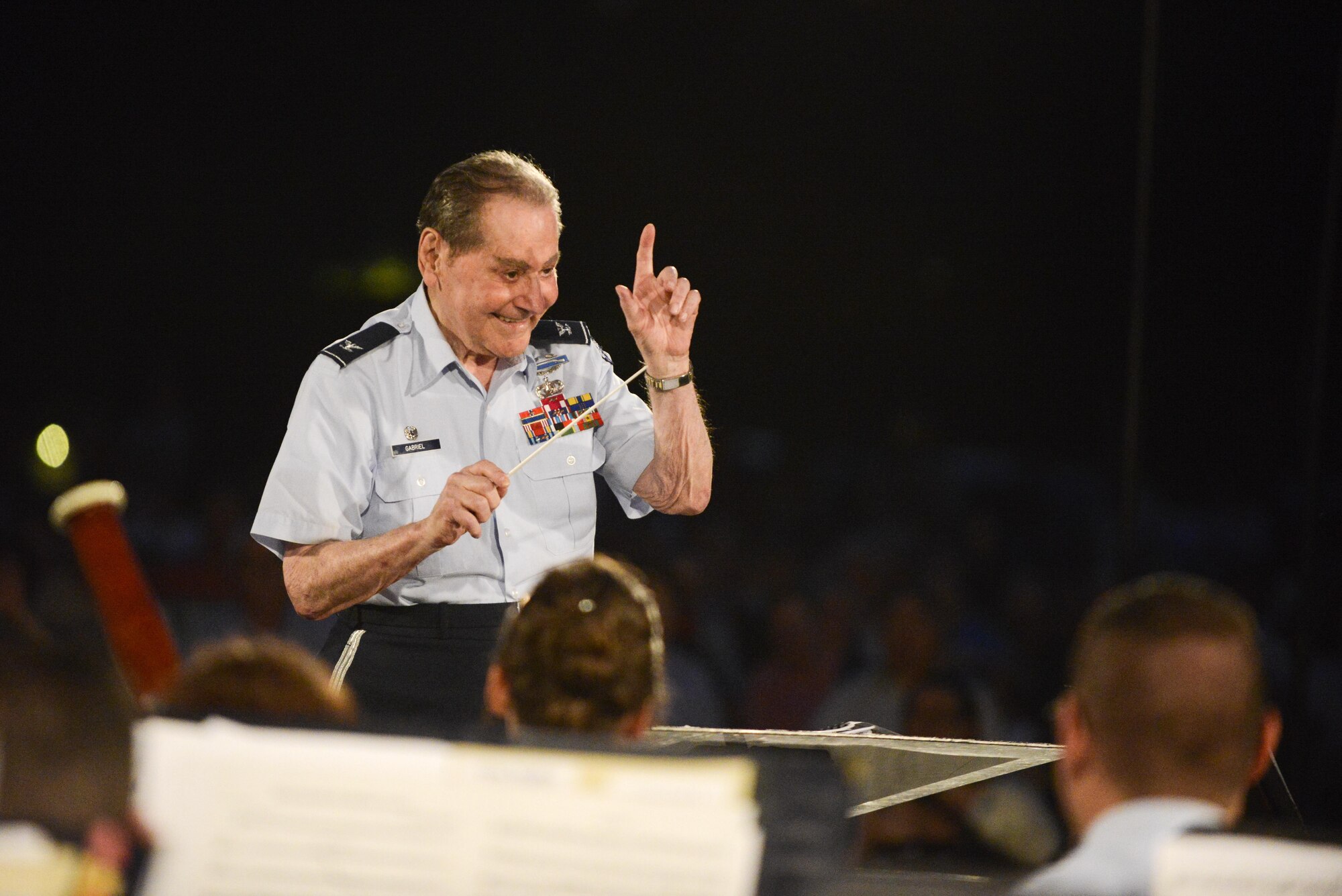 Honorary conductor retired Col. Arnald D. Gabriel leads an Air Force Band performance on a stage beneath the Air Force Memorial in Arlington, Va., Aug. 14, 2015. The band performed music from the World War II era after a wreath-laying ceremony and a flyover to commemorate the 70th anniversary of the end of World War II. (Air Force photo/Tech. Sgt. Joshua L. DeMotts)