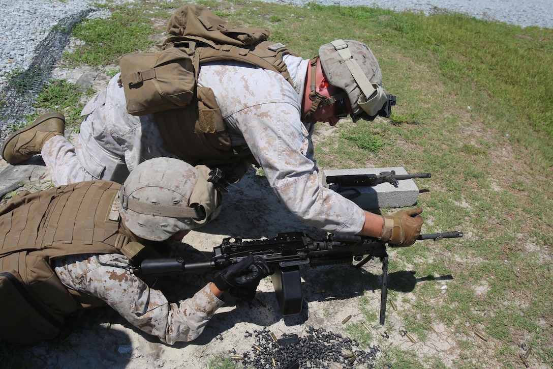 Two Marines with Truck Company, Headquarters Battalion, 2nd Marine Division perform a barrel change on the M249 Squad Automatic Weapon before switching places at a machine gun range aboard Marine Corps Base Camp Lejeune, N.C. Aug. 13, 2015. The basic knowledge of knowing how to change a barrel is necessary in case the weapon goes down.  