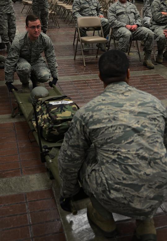 Senior Airman Timothy Burnett, 51st Aerospace Medical Squadron bio-environmental engineer and Senior Airman Jeroyd Gobert, 51st Medical Operations Squadron surgical technician, demonstrate how to lift a litter in order to place it onto a station within a patient staging area on Osan Air Base, Republic of Korea, Aug. 18, 2015.  The patient staging area is where casualties are held before they are moved to a safer location to receive follow-on care. The patient staging area can hold approximately 130 patients. (U.S. Air Force photo/Tech. Sgt. Travis Edwards)