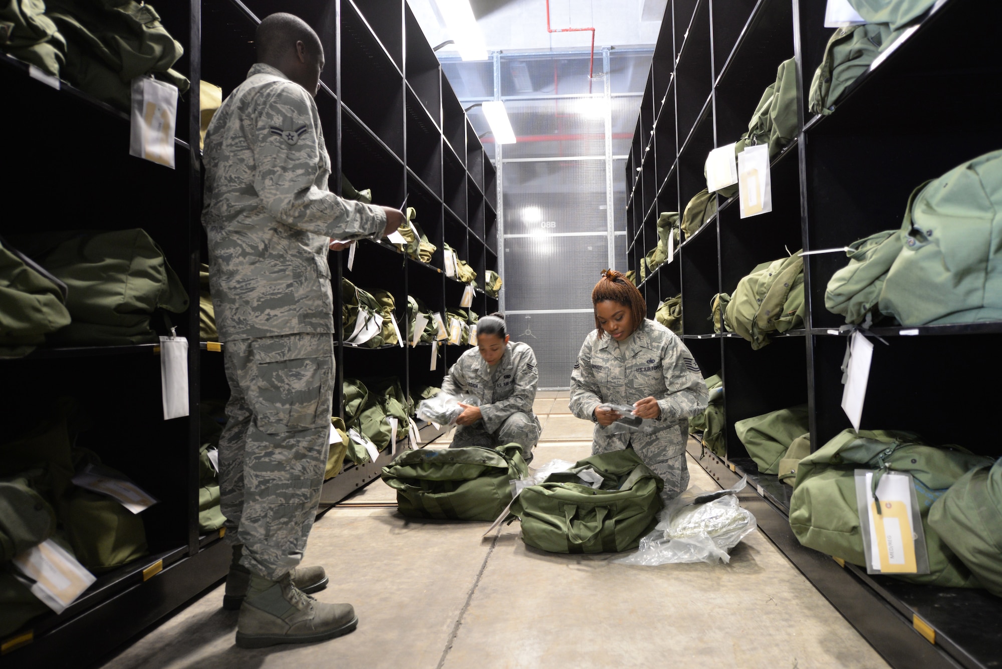 U.S. Air Force members of the 18th Logistics Readiness Squadron Material Management Flight inspect mobility bags of individual protection equipment on Kadena Air Base, Japan, Aug. 13, 2015. The 18th LRS Material Management Flight issues each Kadena Airman IPE for both training and for real-world deployments. (U.S. Air Force photo by Senior Airman Omari Bernard)