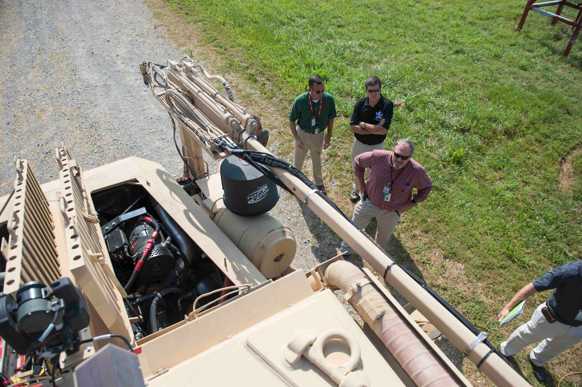 Stakeholders in the recovery of airbases denied by ordnance, or RADBO, vehicle project tour the vehicle before a live demonstration at Redstone Test Center, Alabama, July 16. RADBO uses a three-kilowatt Zeus III laser mounted atop a mine-resistant ambush protected, or MRAP, vehicle, to engage and mitigate unexploded ordnance. (U.S. Air Force photo/Jess Echerri/Released)