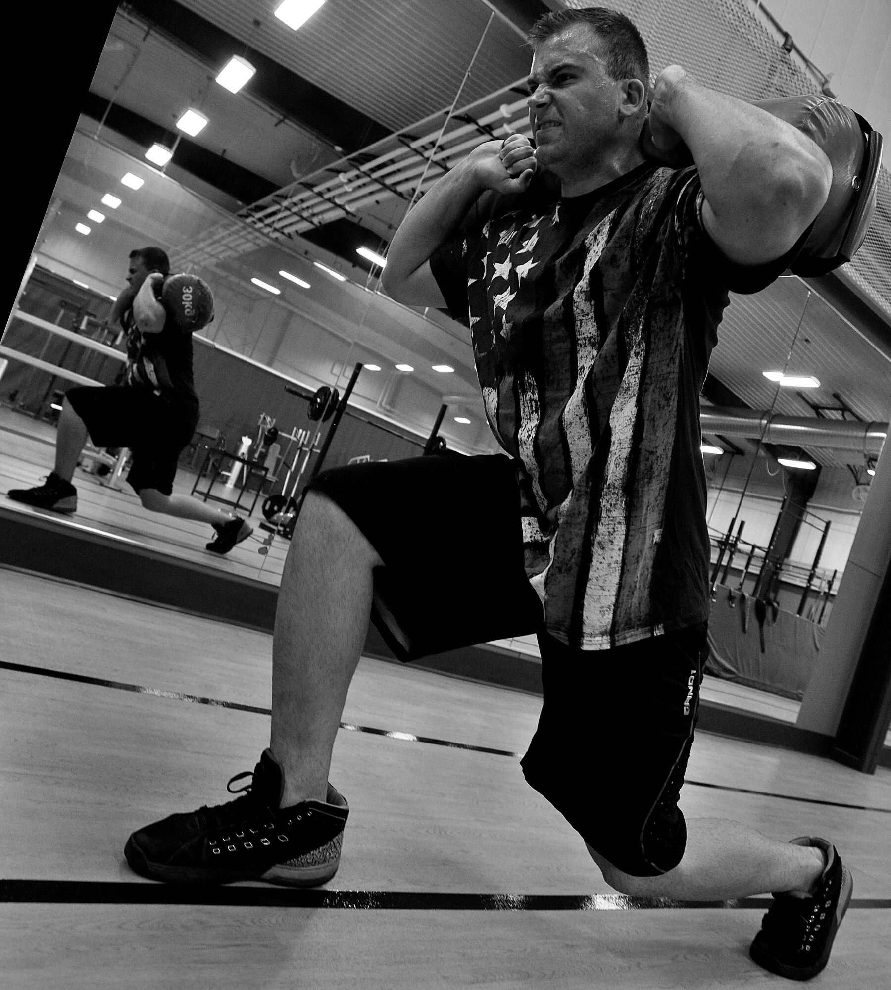 Senior Airman Paul Dell, 319th Logistics Readiness Squadron vehicle operator, lunges a 30-pound sandbag during his leg workout routine at the fitness center on Grand Forks Air Force Base, North Dakota on Aug. 12, 2015. Dell works out to be physically strong which is one of the four pillars of Comprehensive Airman Fitness. To be physically fit, Airmen are able to perform and excel. (U.S. Air Force photo by Senior Airman Xavier Navarro/released)