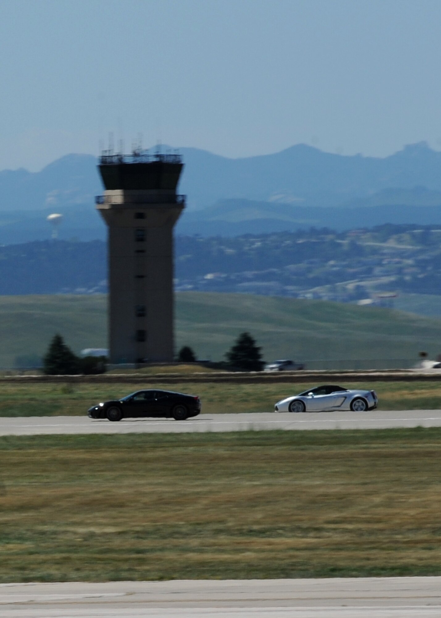 A Precision Exotics Ferrari and Lamborghini speed down the flightline during the 2015 Dakota Thunder airshow and open house at Ellsworth Air Force Base, S.D., Aug. 15, 2015. Precision Exotics partners with airshows to bring unique performances, such as car vs. car and car vs. plane runway races, to audiences around the world and were one of the scheduled events during both days of the show. (U.S. Air Force photo by Senior Airman Hailey R. Staker/Released)