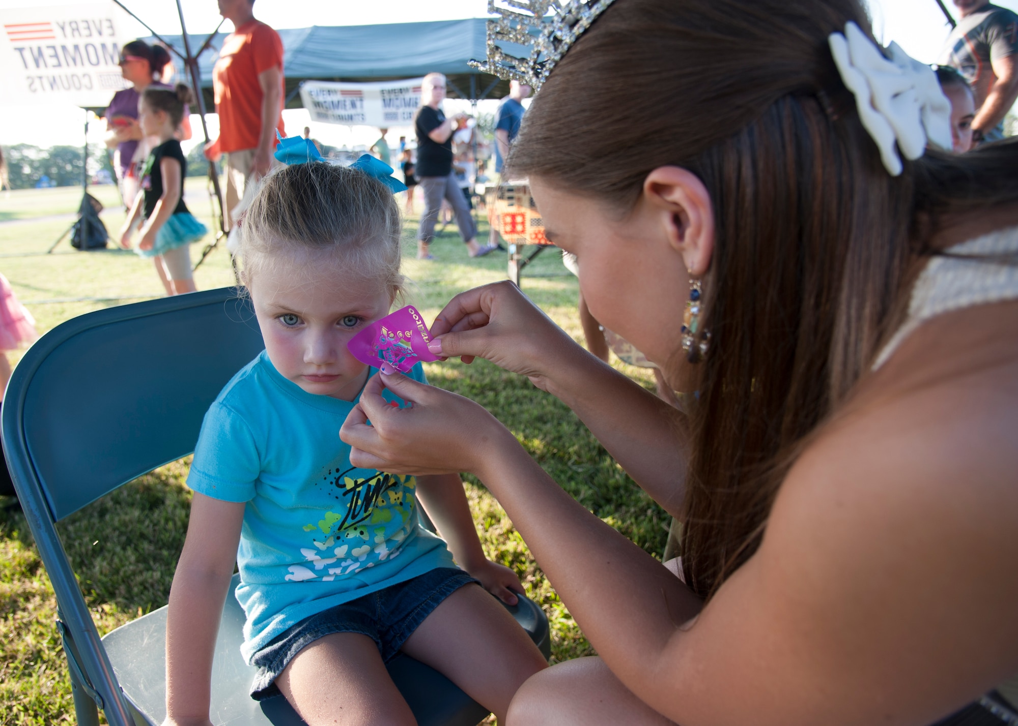 Brooke Mitchell, Miss Delaware 2015, prepares to remove a stencil from the face of Brooklynn Evans, daughter of Staff Sgt. Jason Evans, 436th Civil Engineer Squadron, during the USO Delaware Movie on the Lawn event Aug. 14, 2015, across from the Youth Center on Dover Air Force Base, Del. Mitchell helped out at a face painting booth that was one of the numerous activities provided prior to the evening showing of “Finding Nemo.” (U.S. Air Force photo/Master Sgt. Jeremy Larlee)