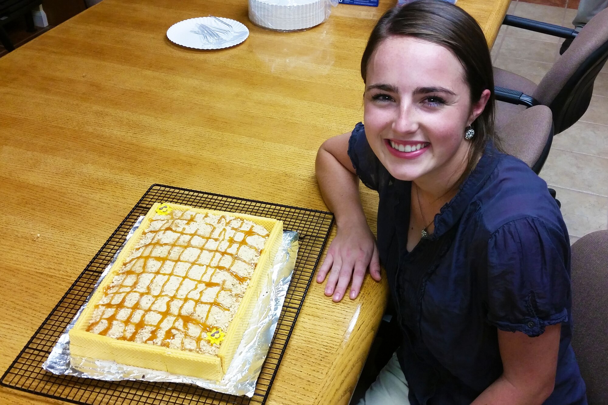Kathleen Rish, a senior at Port Saint Joe High School in Port Saint Joe, Florida, poses next to a sandbox cake after the completion of her eight-week internship with the research and acquisitions division of the Air Force Civil Engineer Center’s Readiness Directorate. During her internship, Rish researched biocementation, a process that uses bacteria to harden sand into rocks. (U.S. Air Force photo/Jess Echerri/Released)
