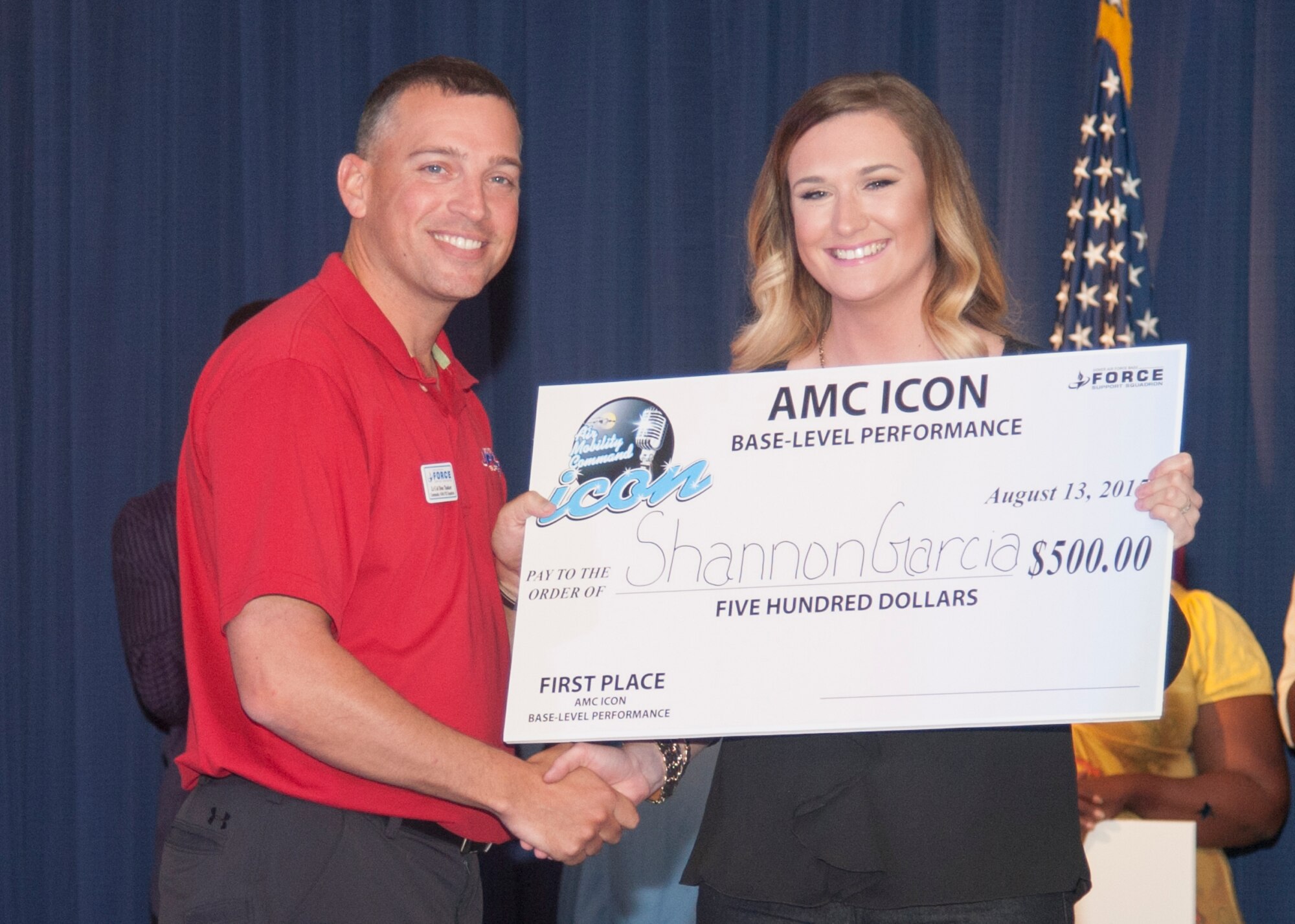 Lt. Col. Donald Tasker, 436th Force Support Squadron commander, left, presents Shannon Garcia, wife of Senior Airman Tyler Garcia, 436th Aircraft Maintenance Squadron, with a check for $500 August 13, 2015, at the Landings Club on Dover Air Force Base, Del. The $500 was the first place award for the Air Mobility Command Icon competition at Dover AFB. (U.S. Air Force photo/Senior Airman Jared Duhon) 