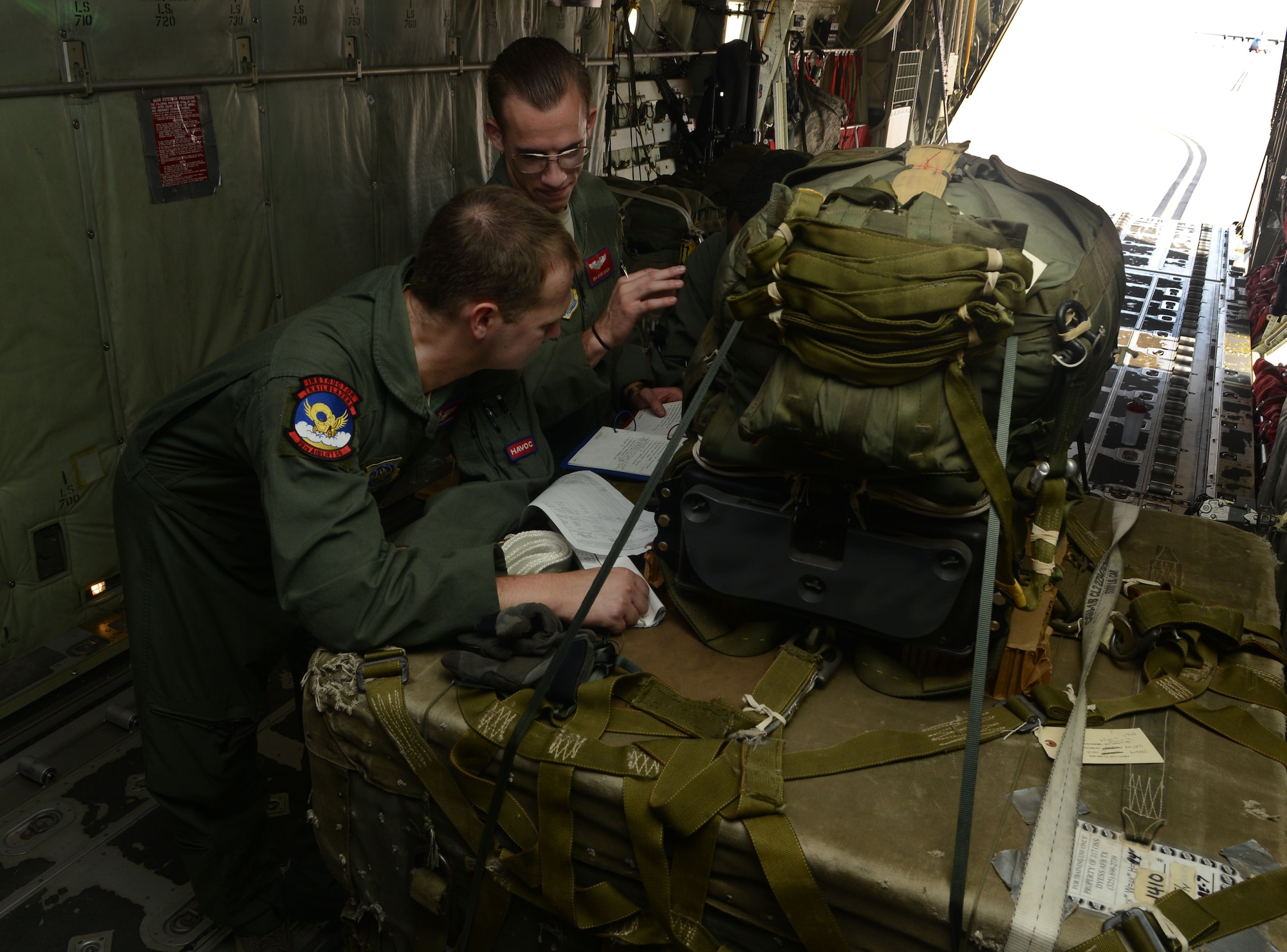 U.S. Air Force Staff Sgt. Scott McGuire, left, and Senior Airman Ryan Usher, both 39th Airlift Squadron loadmasters, review instructions on how to perform a Joint Precision Airdrop System airdrop, July 29, 2015, at Dyess Air Force Base, Texas. A JPADS is an airdrop bundle that is enhanced with the use of Global Positioning System (U.S. Air Force photos by Airman 1st Class Autumn Velez/Released).