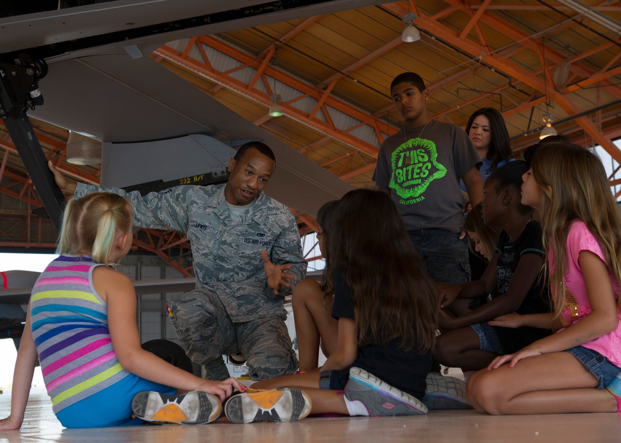 Senior Airman Jason Lewis, a 49th Aircraft Maintenance Squadron MQ-1 Predator crew chief, answers questions about the MQ-1 to children during a base tour at Holloman Air Force Base, N.M. on Aug. 12. The Holloman Youth Center received a hands on tour of Holloman to learn about the various missions Team Holloman supports. The tour was also part of the Tuskegee Airmen Initiative that supports children’s interest and knowledge in fields of aviation. (U.S. Air Force photo by Senior Airman Leah Ferrante)