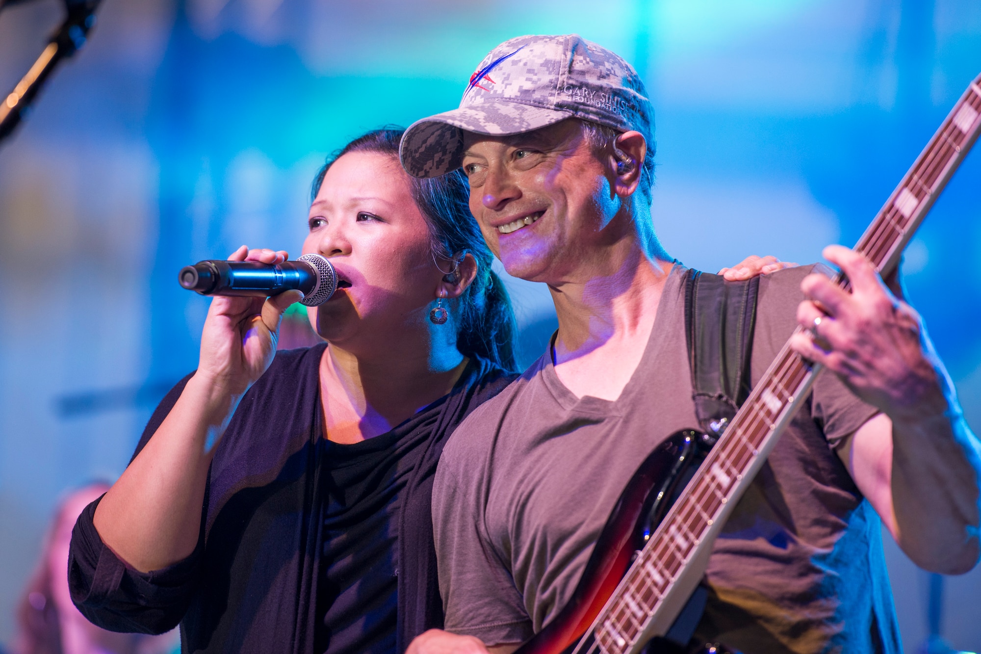 Gary Sinise plays electric bass next to vocalist Mari Anne Jayme during the Lt. Dan Band performance in Dock 1 at Minot Air Force Base, N.D., Aug. 15, 2015. The Gary Sinise Foundation partnered with the United Service Organizations to perform at Whiteman, Minot and Malmstrom in one weekend. (U.S. Air Force photo/ Airman 1st Class Justin T. Armstrong)