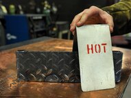 An Airman from the 5th Maintenance Squadron places a warning sign over a hot piece of metal at Minot Air Force Base, N.D., Aug. 14, 2015. The welding shop takes safety seriously due to the weight of the materials they handle; burn risk from hot metal and the crippling effects a welding arc can have on a person’s eye sight. (U.S. Air Force photo/Senior Airman Stephanie Morris)
